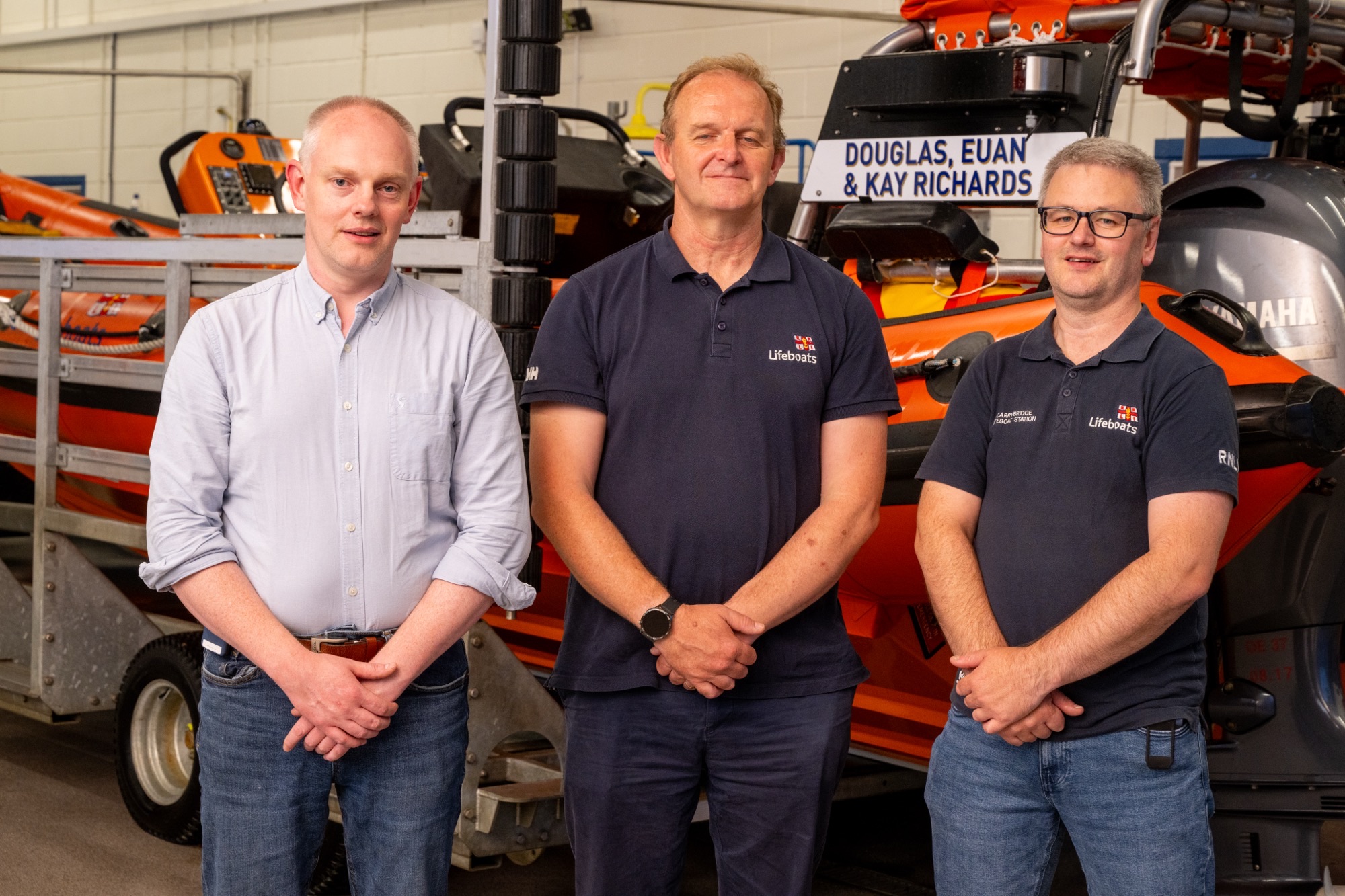 Photograph of Eamonn McManus, Navigator, Sean Ginnelly, Coastal Lifeboat Trainer and Ronnie Heslop, Navigator standing in front of Carrybridge Lifeboat