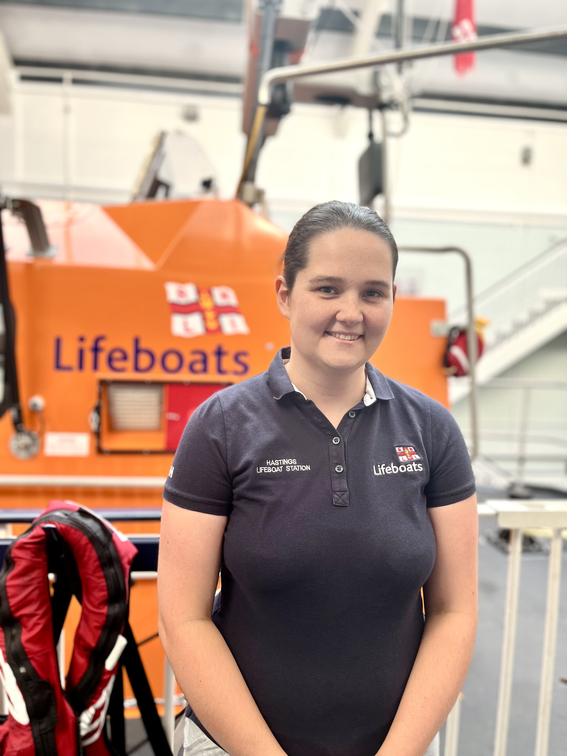 RNLI volunteer standing in front of lifeboat