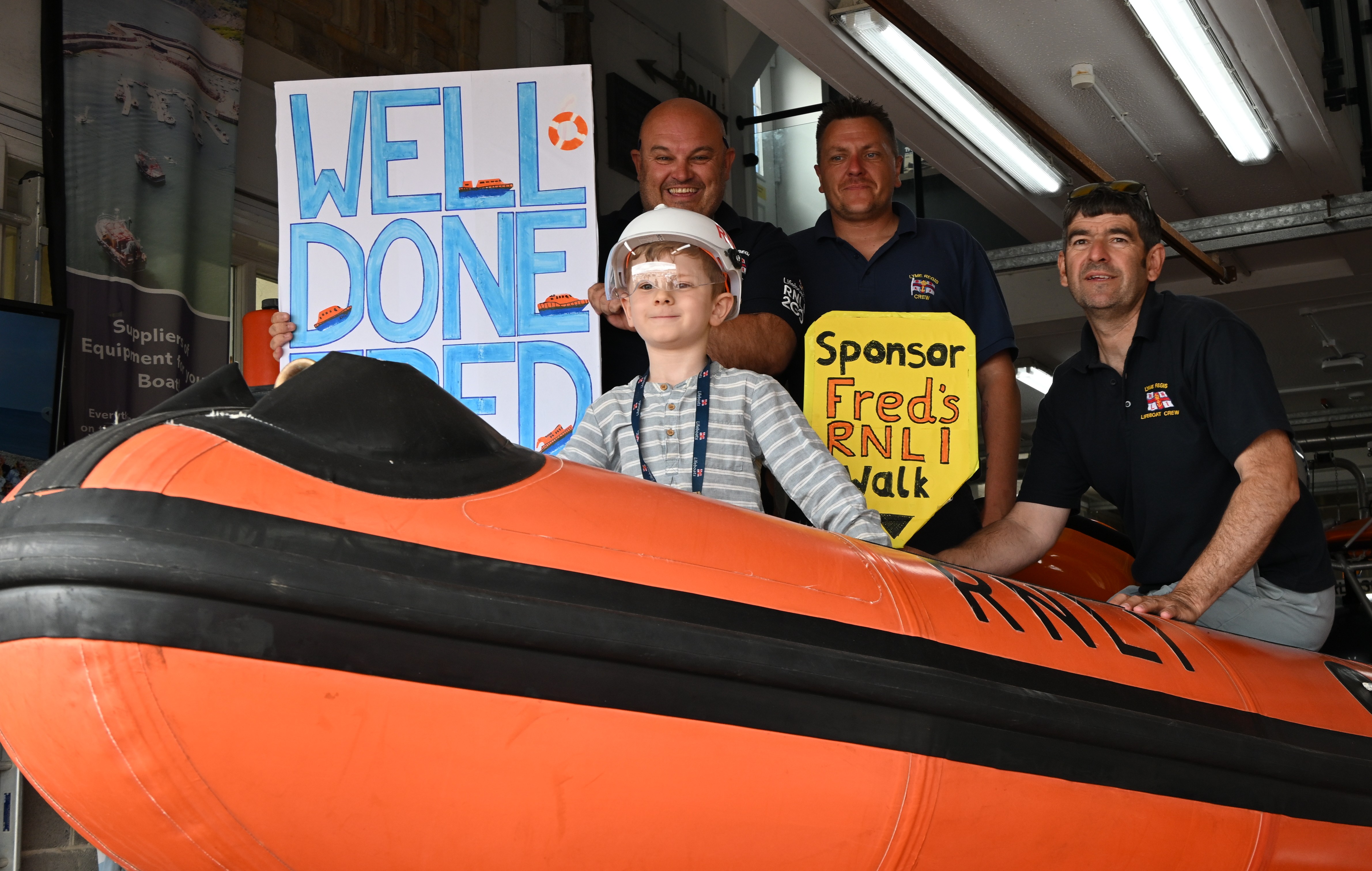 Boy with blue and white sign and lifeboat crew onboard orage boat