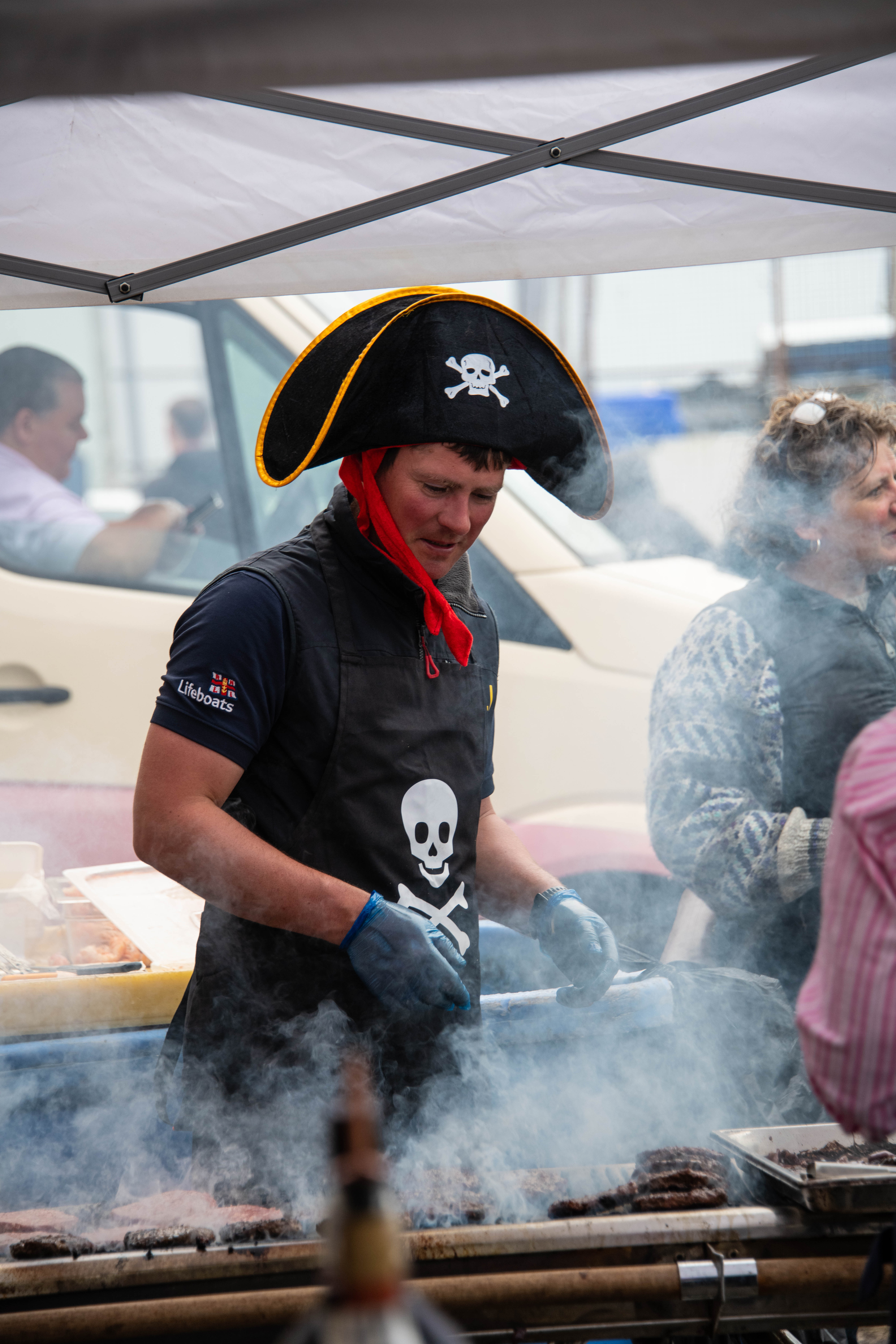 The RNLI Mallaig Coxswain, David Fergusson, is dressed in a pirate hat and apron as he cooked over a smoky BBQ.