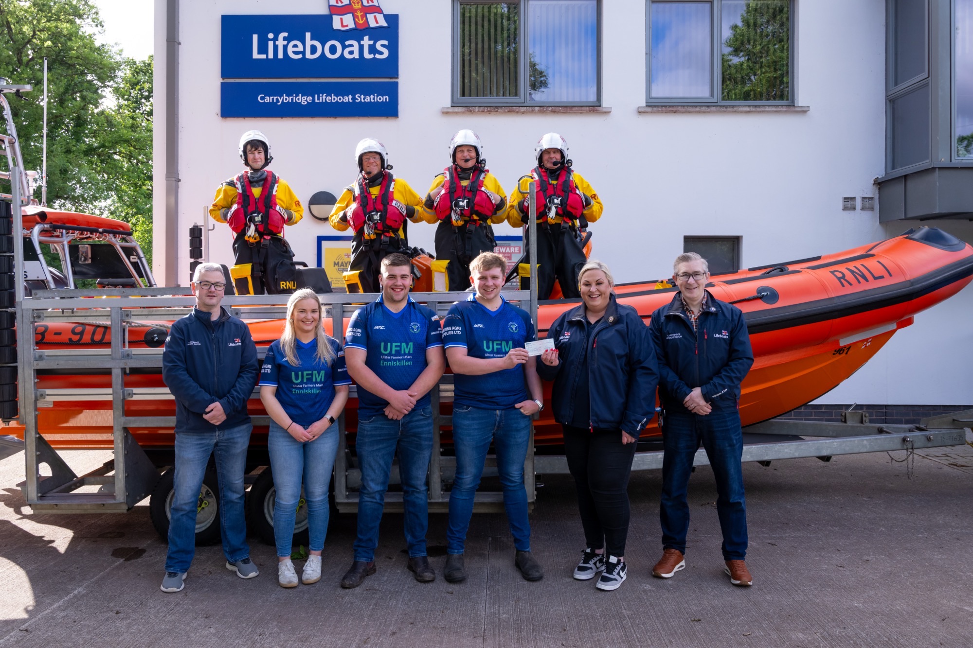 Lisbellaw Young Farmers Club members handing over £1100 cheque to Emma Burton and Ronnie Heslop. 4 crewmembers also pictured standing in the lifeboat.
