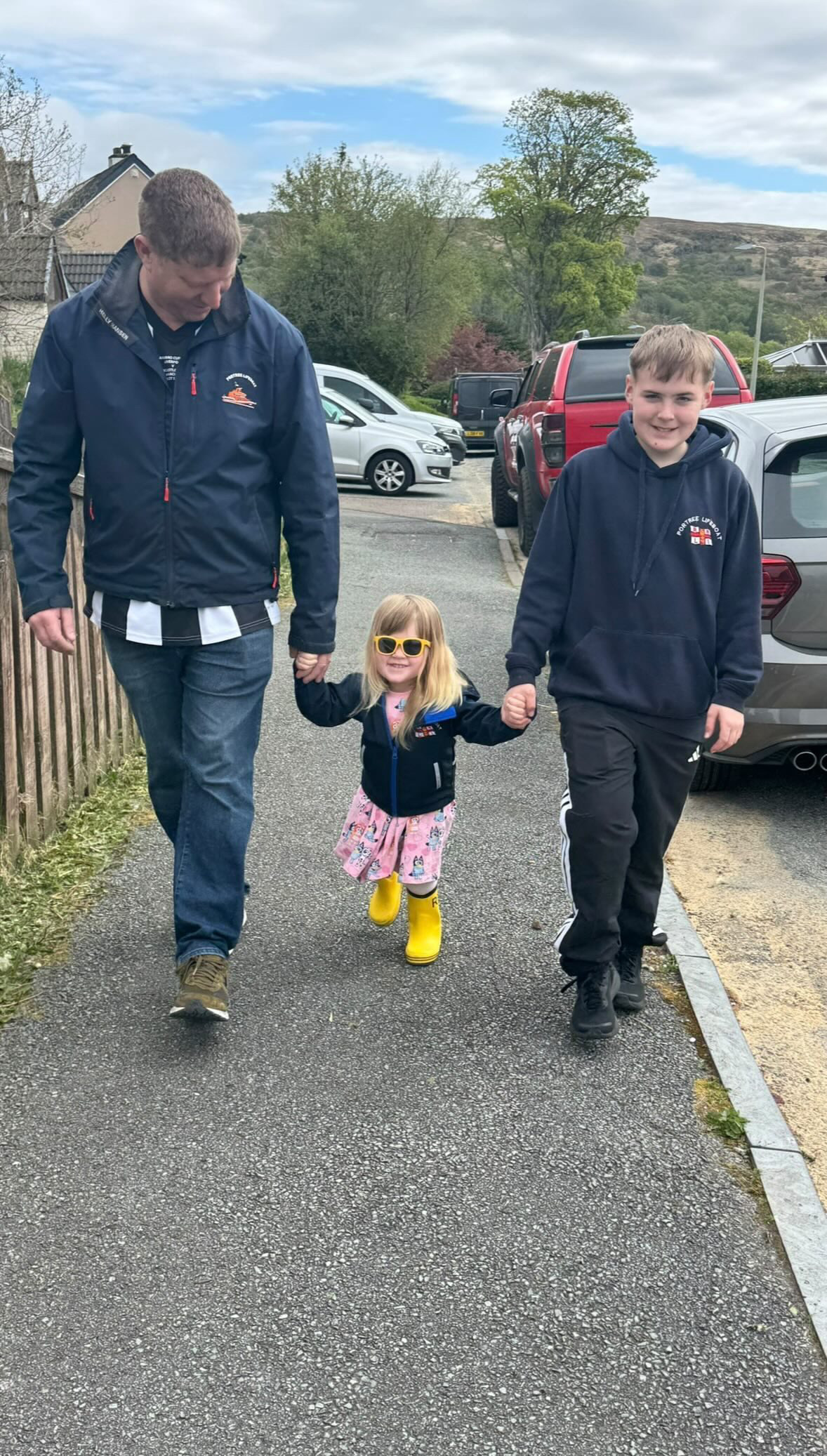 Georgie pictured between dad Brian and brother Angus walking on the pavement