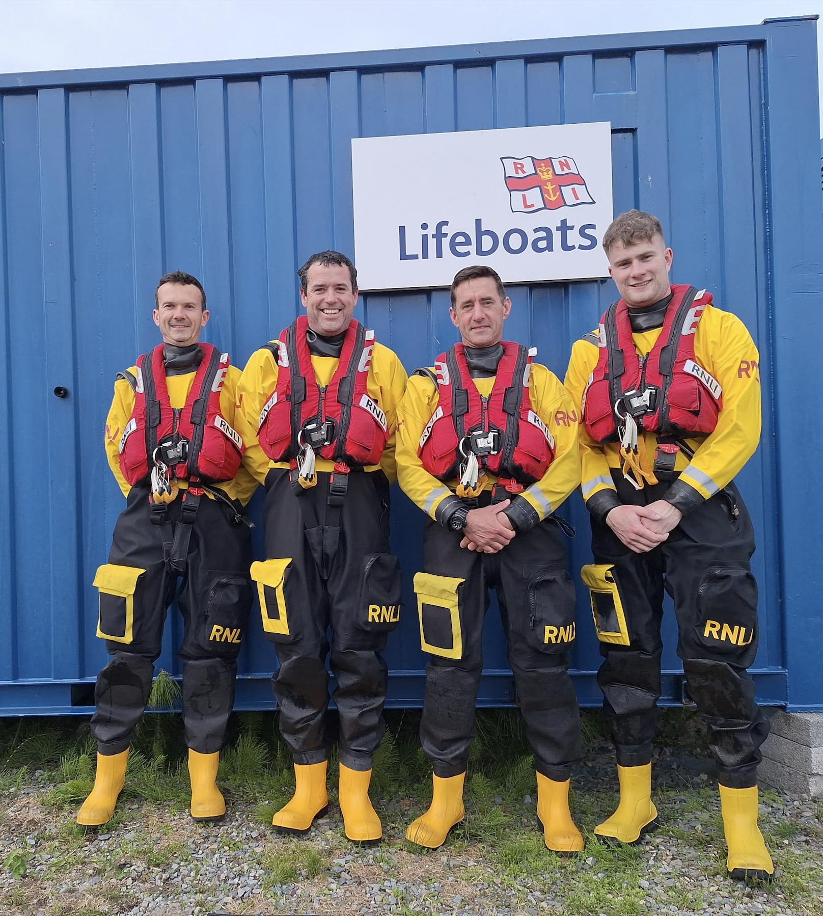 Four RNLI members stand in a line facing the camera in full RNLI kit