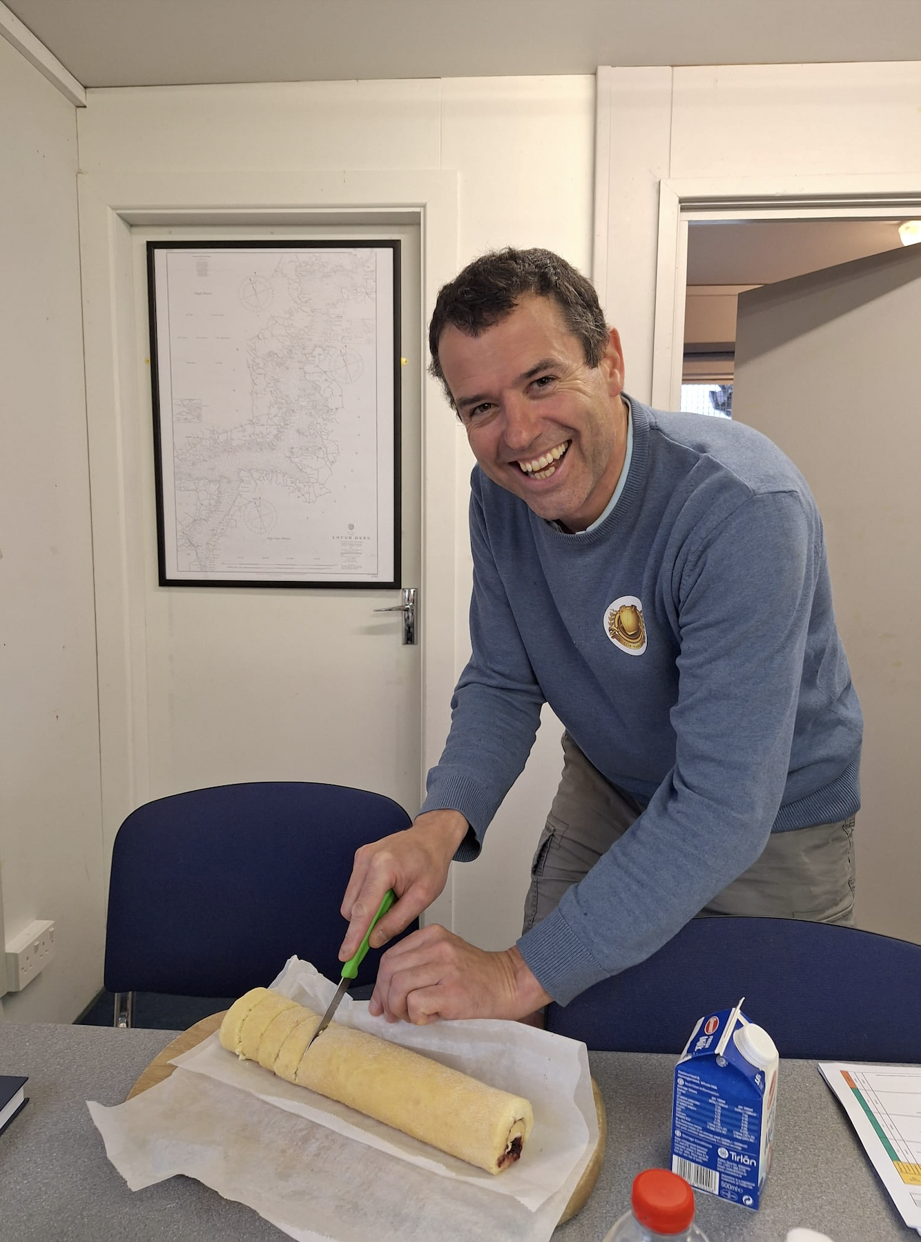 Paraic, newly qualified crew is cutting a swiss roll cake made by the Lifeboat Operations Manager to mark his success