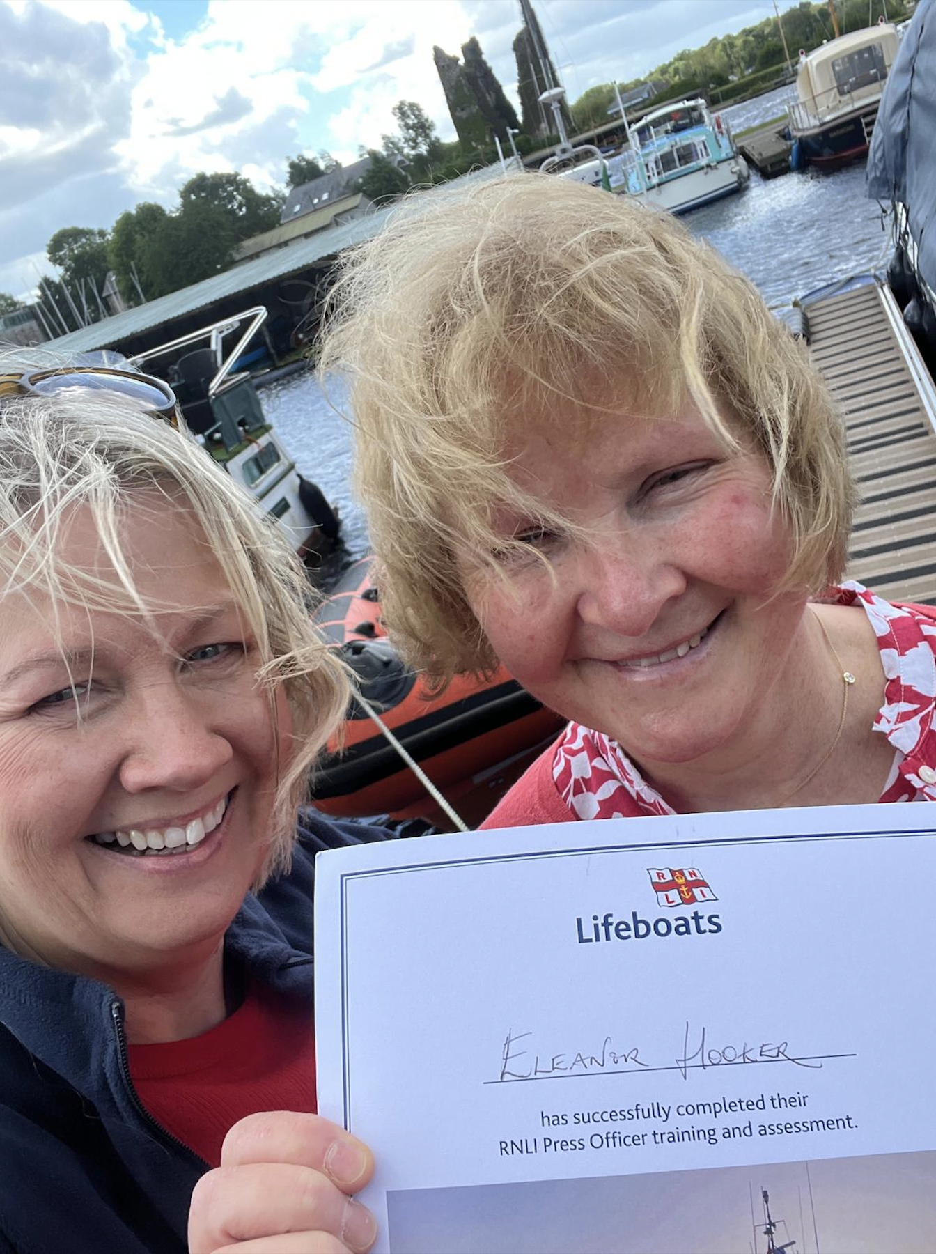 Siobhan and Eleanor smiling into camera holding Eleanor's certificate showing she has passed her assessment as Lifeboat Press Officer