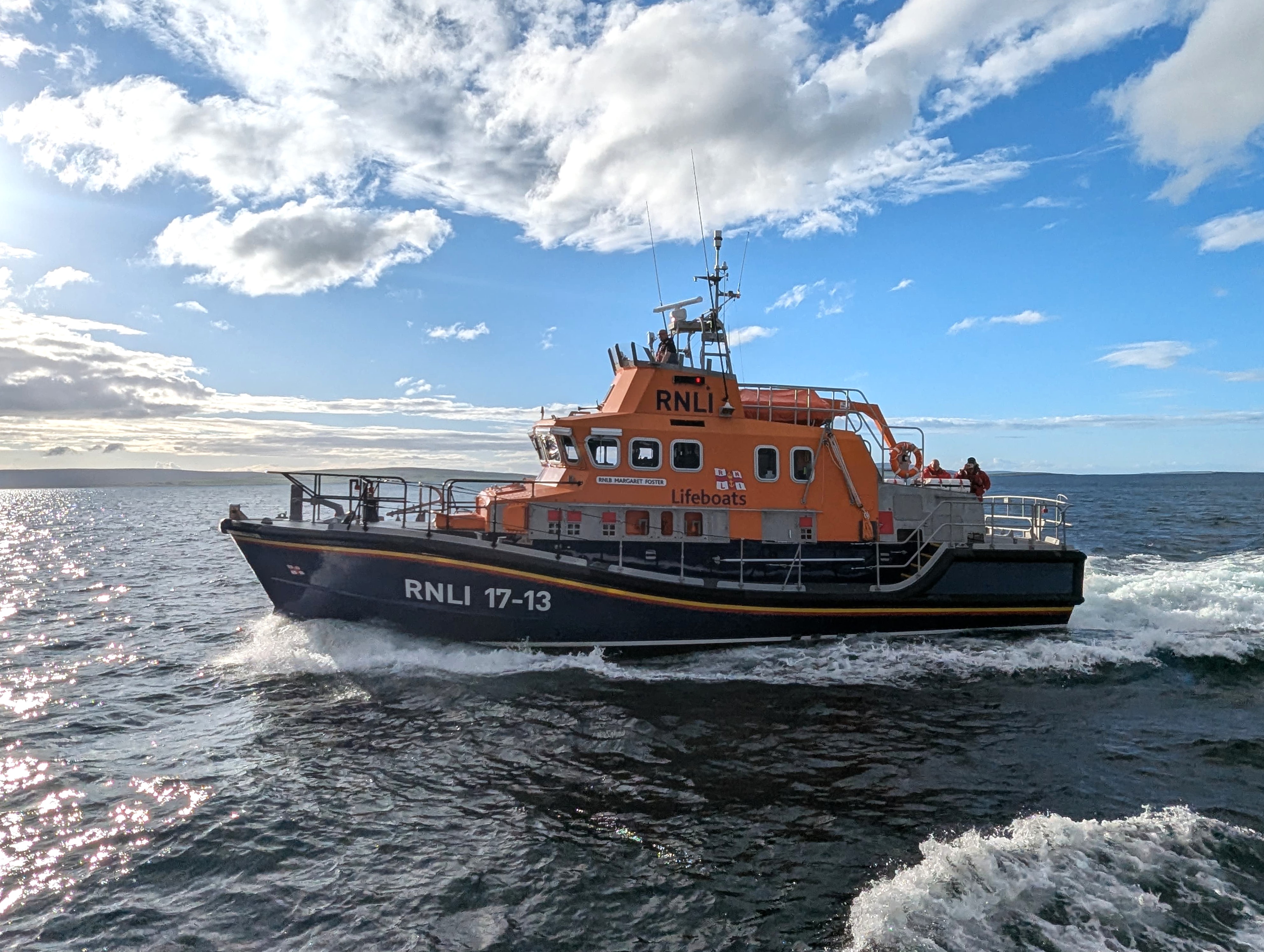 RNLB Margaret Foster motoring through Kirkwall Bay in calm seas on a sunny evening
