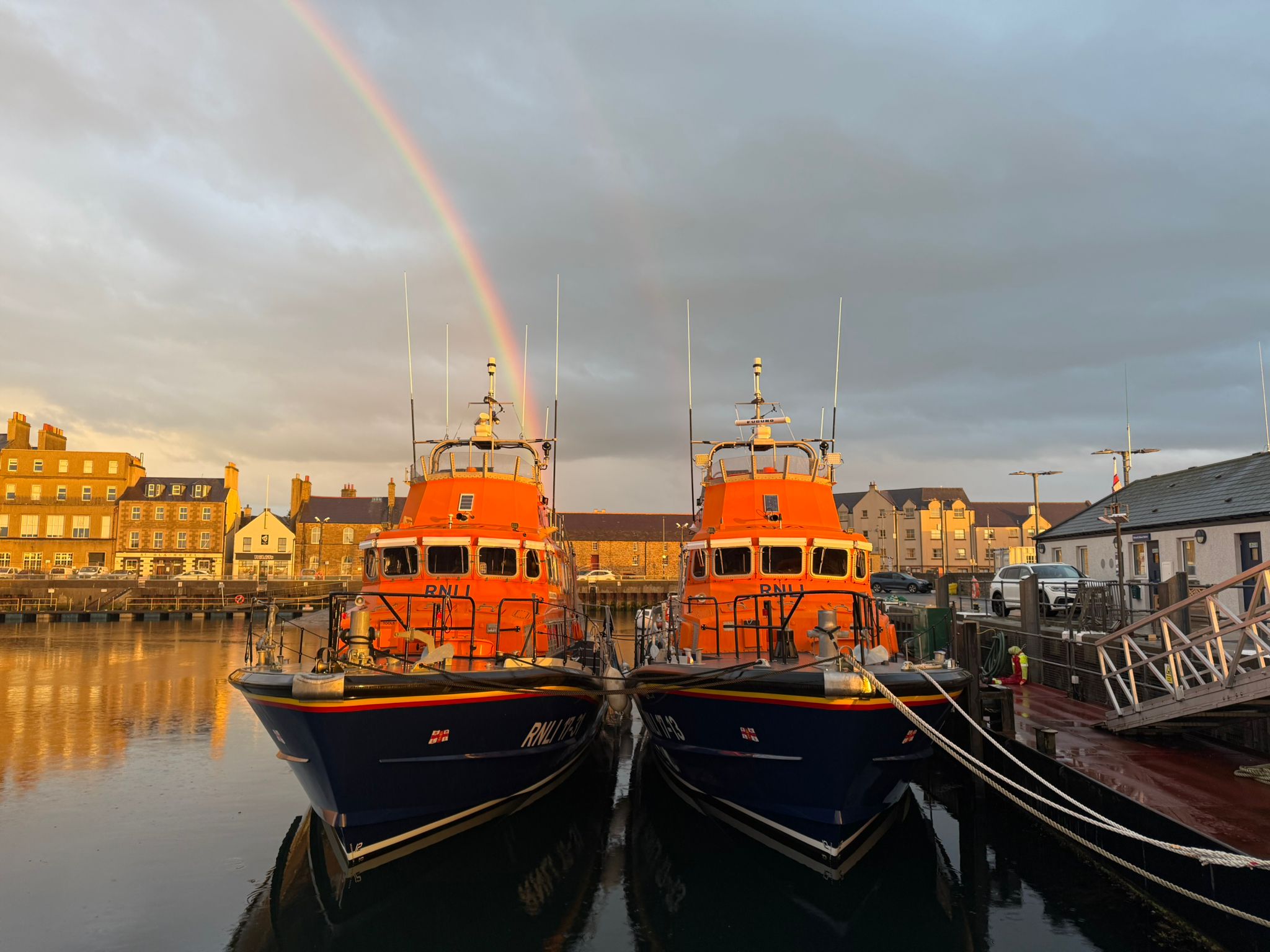 Two RNLBs (Roger and Joy Freeman and Margaret Foster) berthed side by side at West Pier Kirkwall, it is late evening with a rainbow above