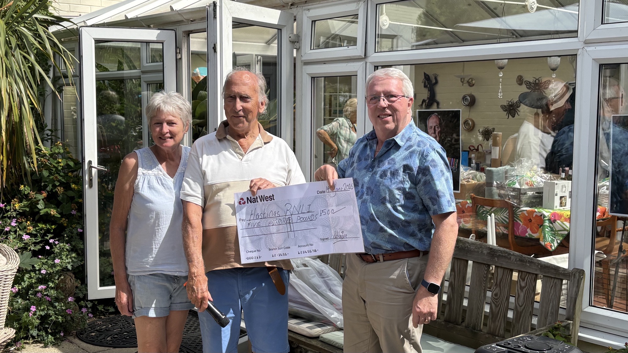 three people standing and holding a large presentation cheque
