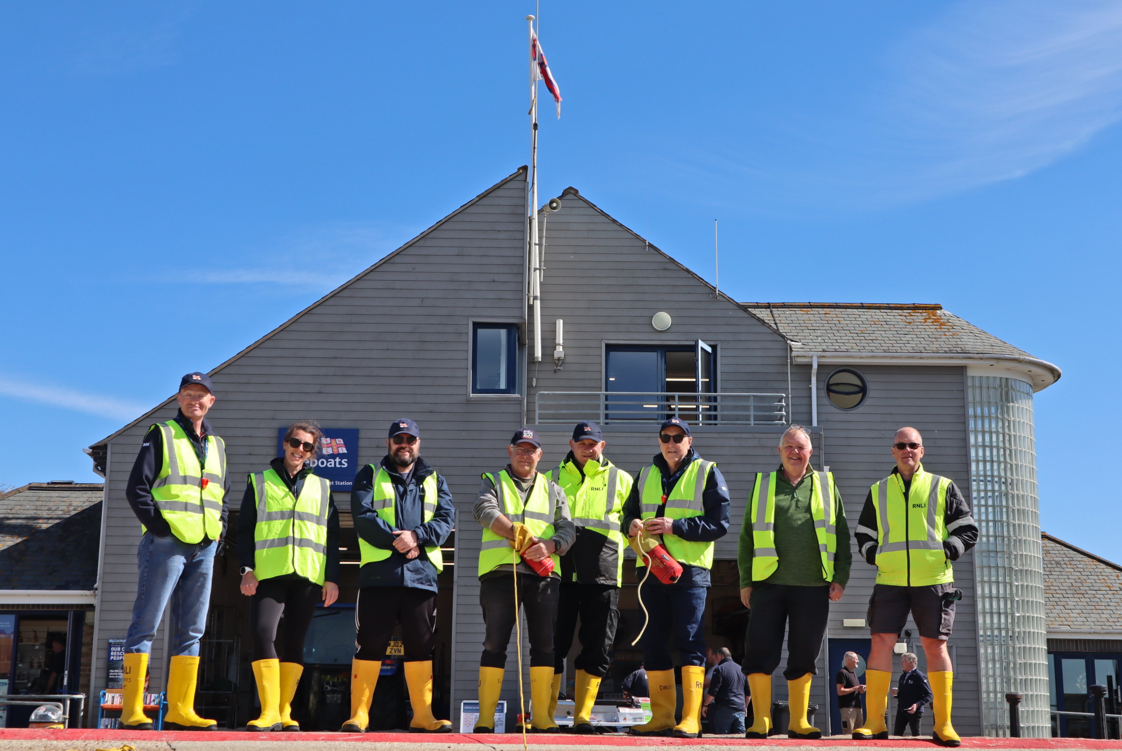 Eight volunteer shore crew stand in front of Littlehampton RNLI Lifeboat Station