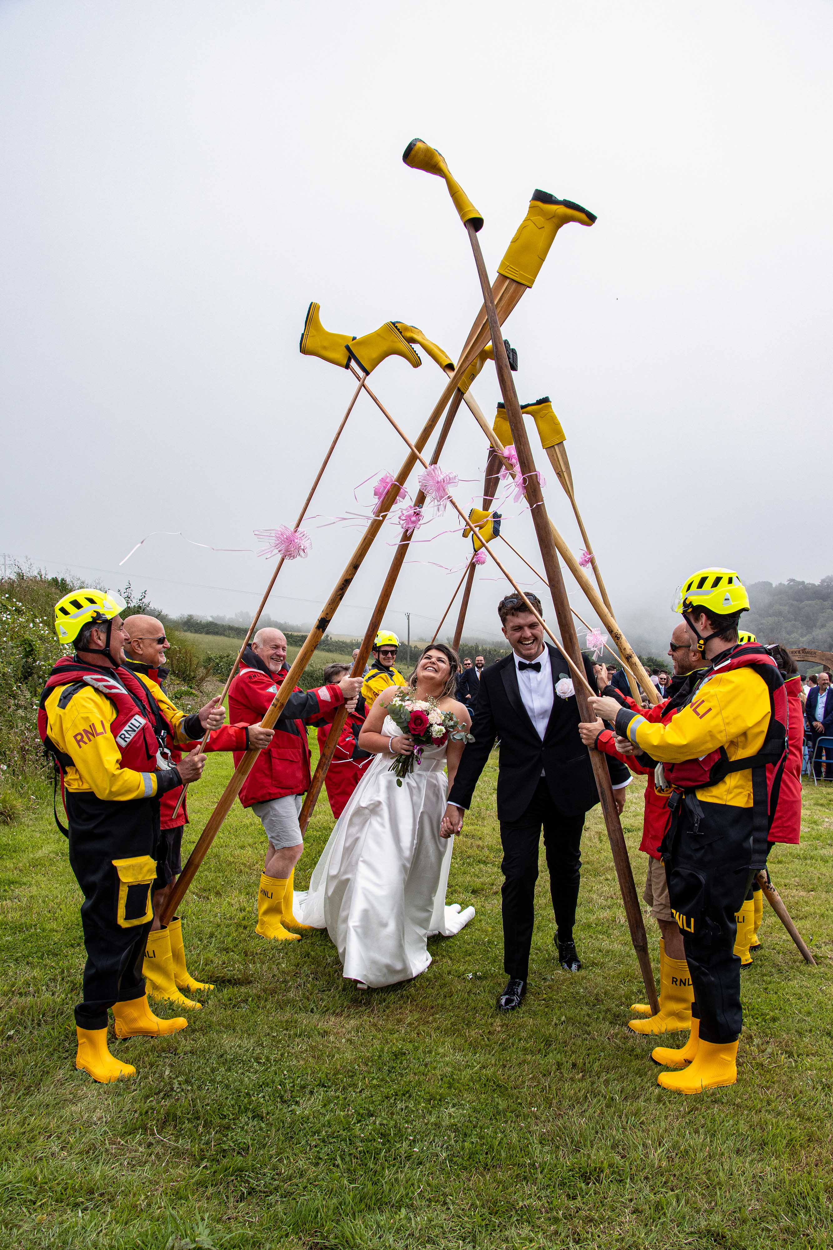 Amber and Alex Richardson walking through Looe RNLI’s yellow welly guard of honour after their marriage