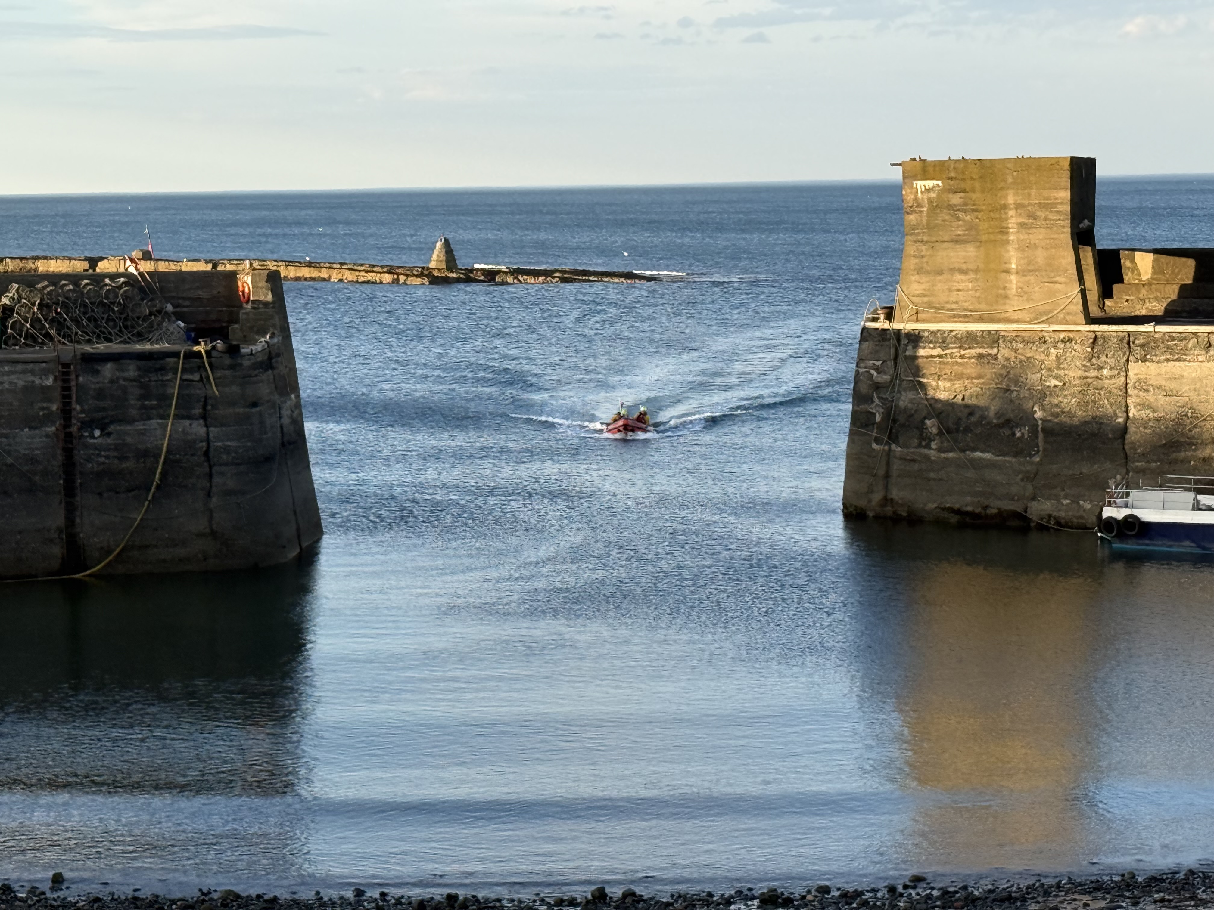 The RNLI D Class lifeboat returning to craster harbour between the piers 