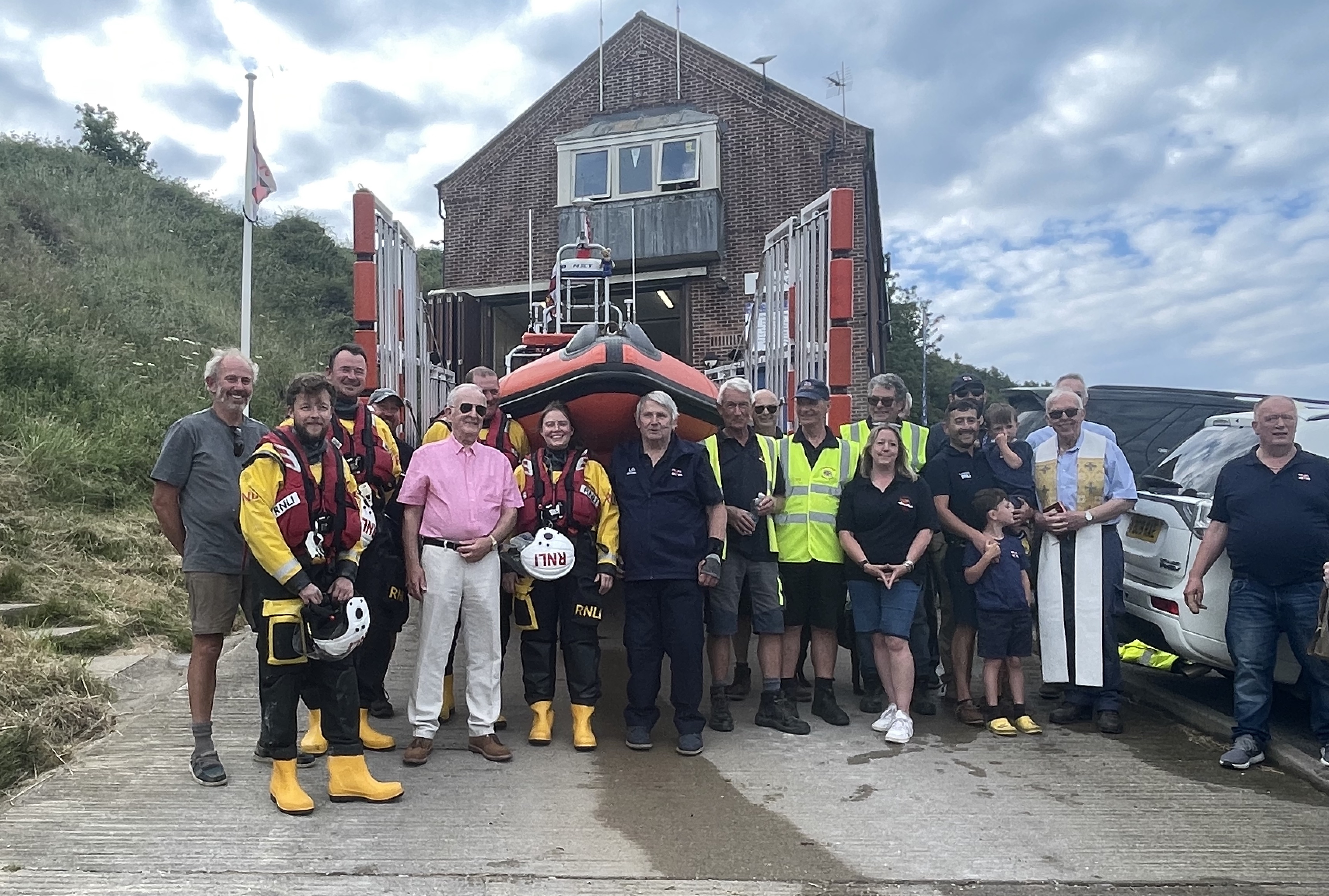 A group of volunteers crew and others in from of the boat on its trailer.