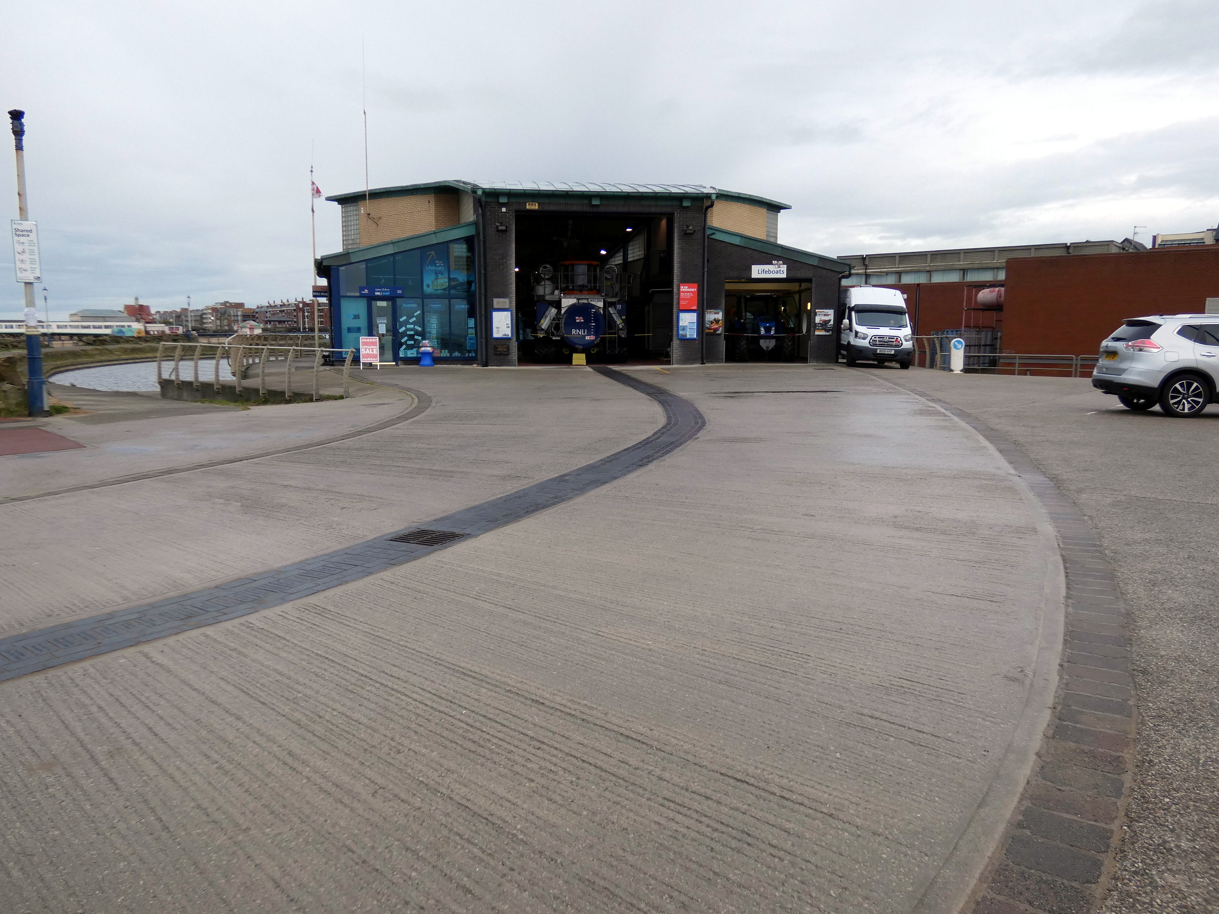 A boathouse with three lines of pavers in the apron in front of it
