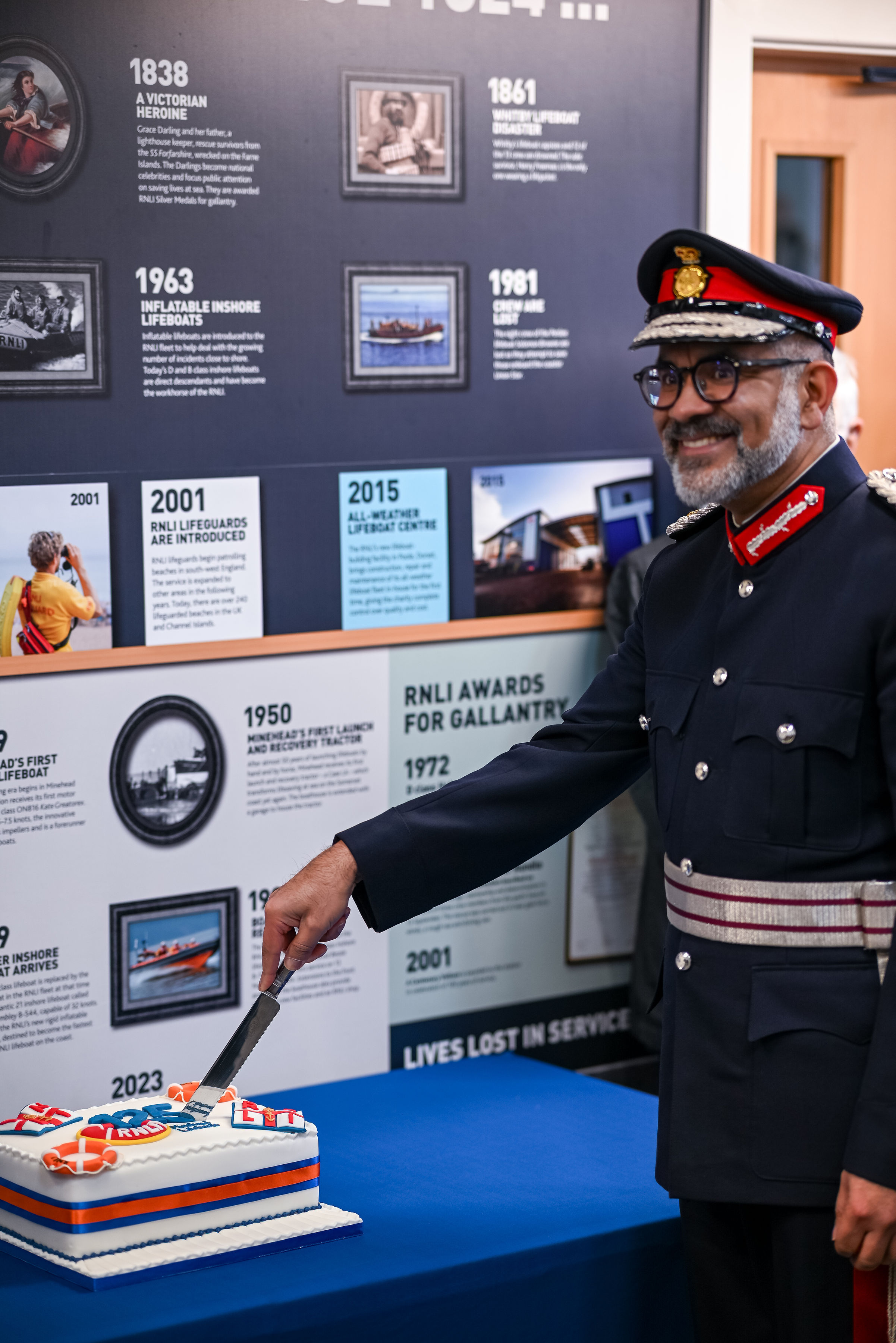 A man in ceremonial uniform cuts a celebration cake