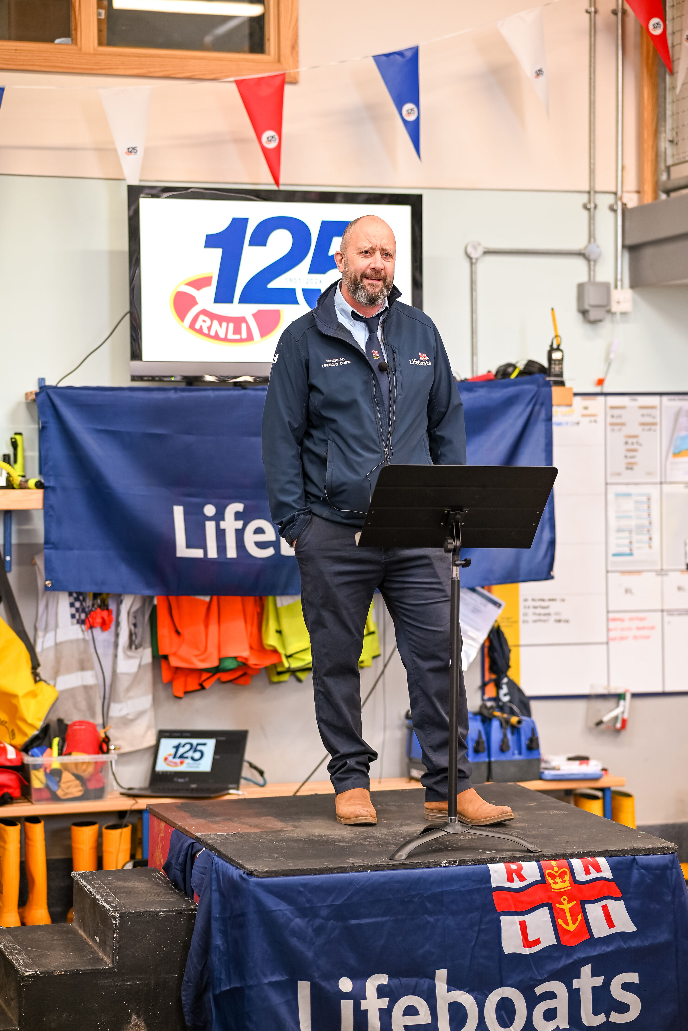 A man in Minehead Lifeboat uniform is explaining rescues to the audience.