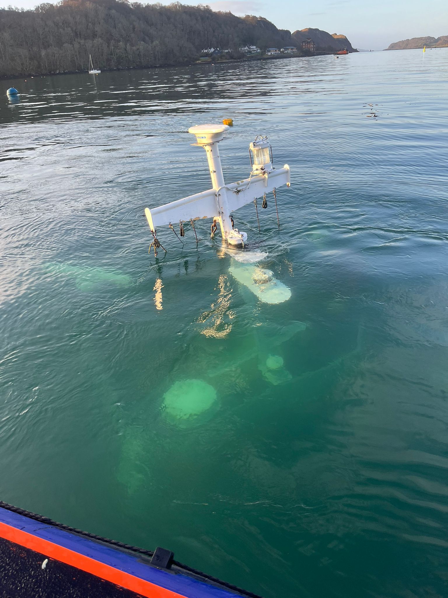 The radar array on the top of the mast of the workboat can just be seen below the blue green water surface