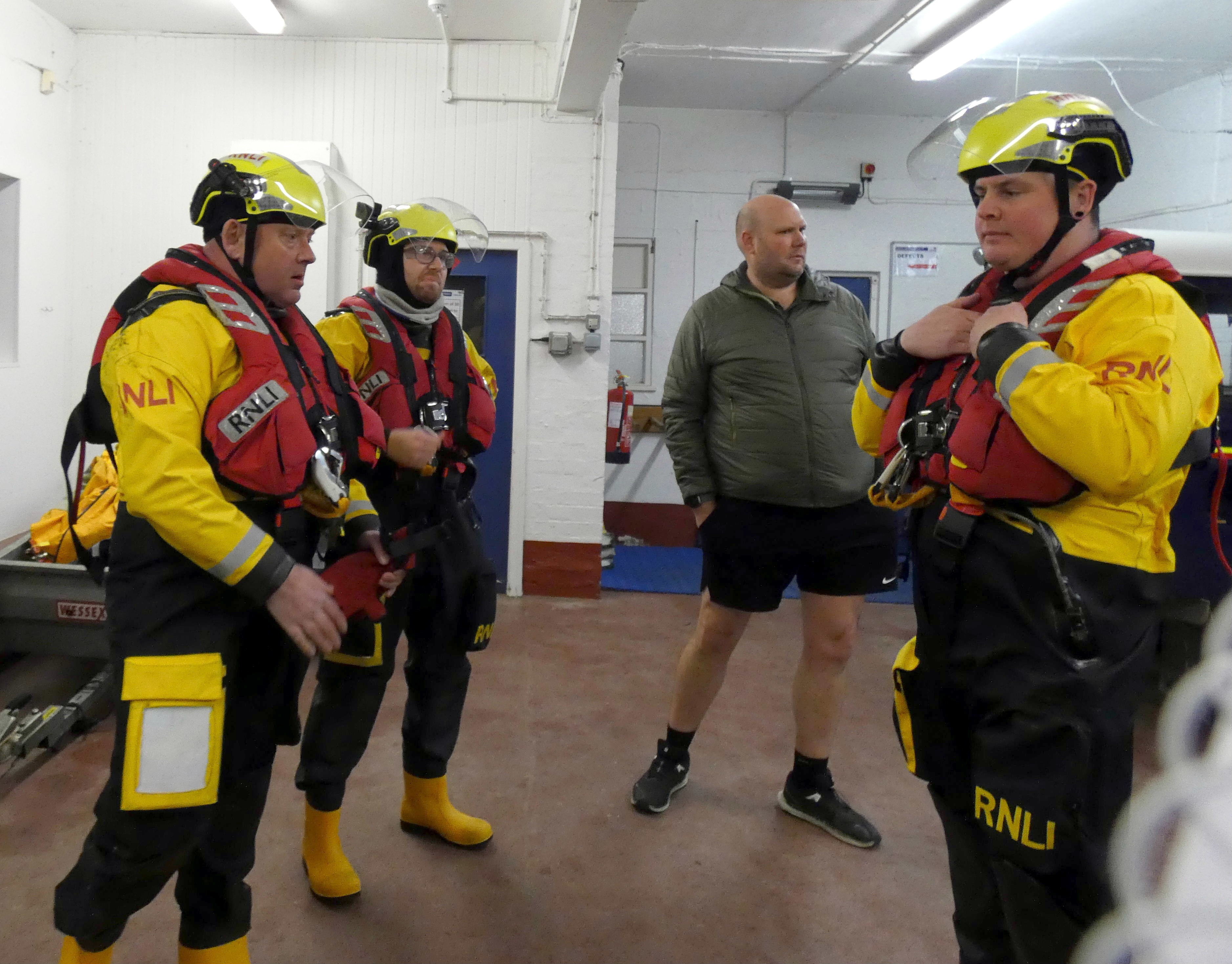 three crew members are briefed with the Coxswain looking on 