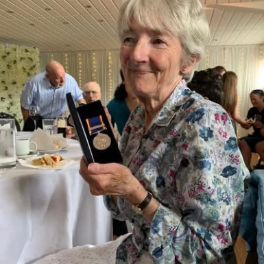 Annie Hemmingway holding a long service medal at a celebration ceremony