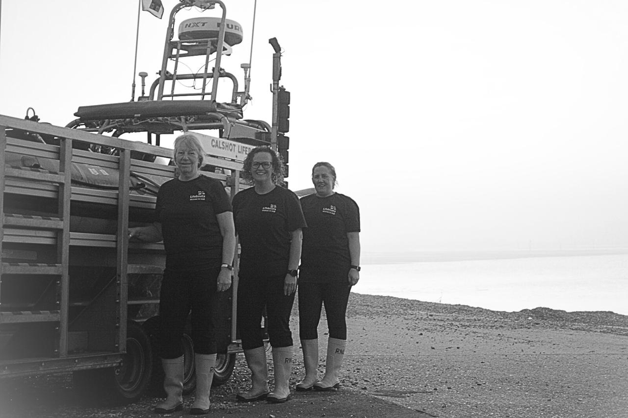 3 women wearing Women in SAR T-shirts and RNLI wellies stood next to Calshots B-Class Lifeboat, Max Walls