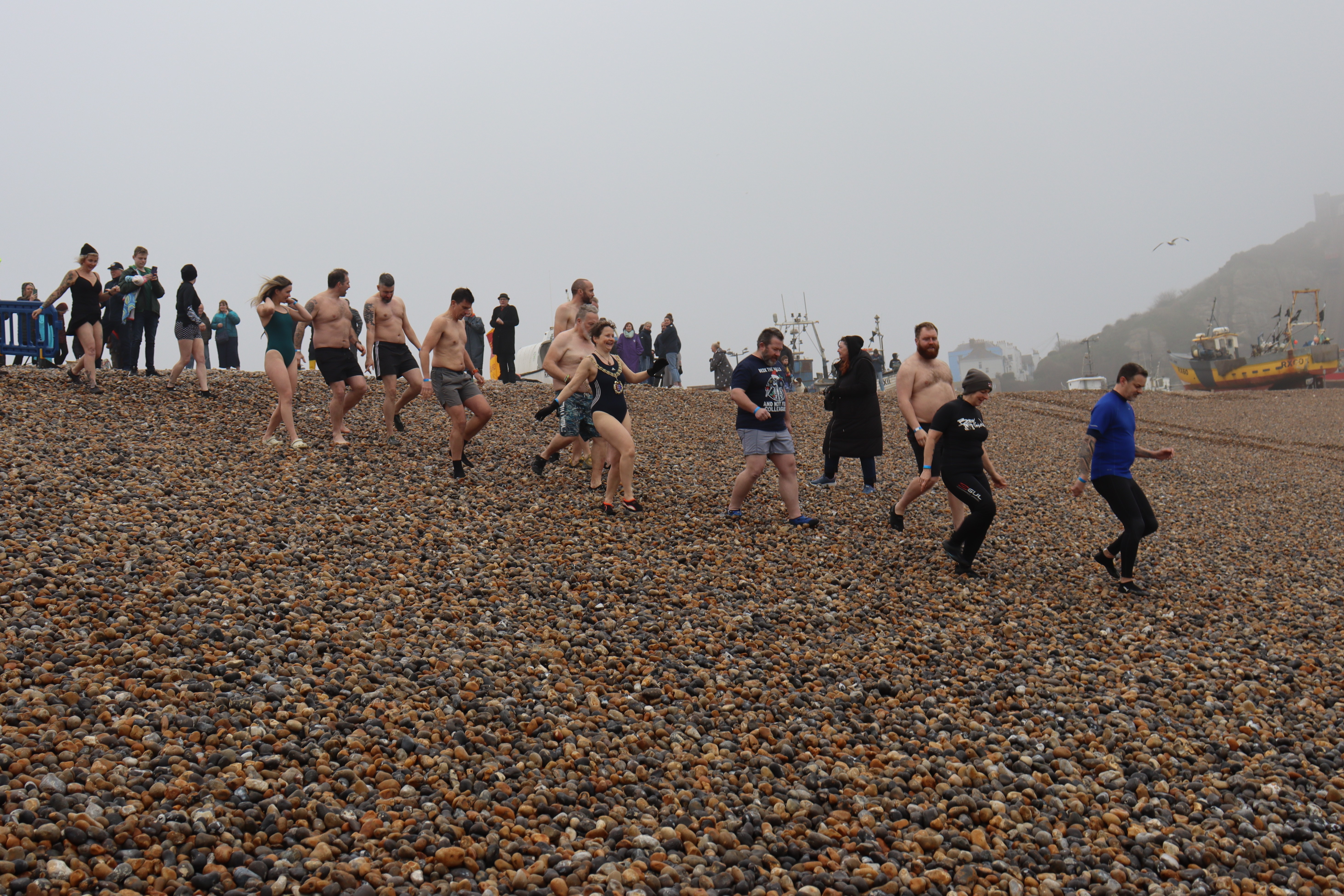 Members of Hastings RNLI crew running down the beach in the sea wear