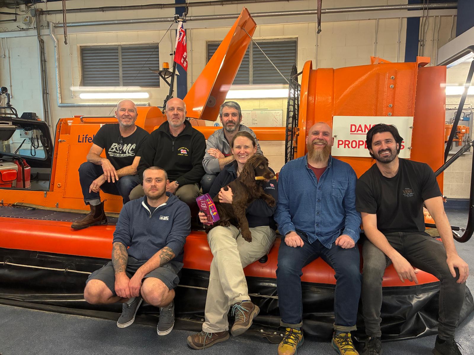 Some of the successful RNLI volunteers sitting on the hovercraft with Rosie and Freddie