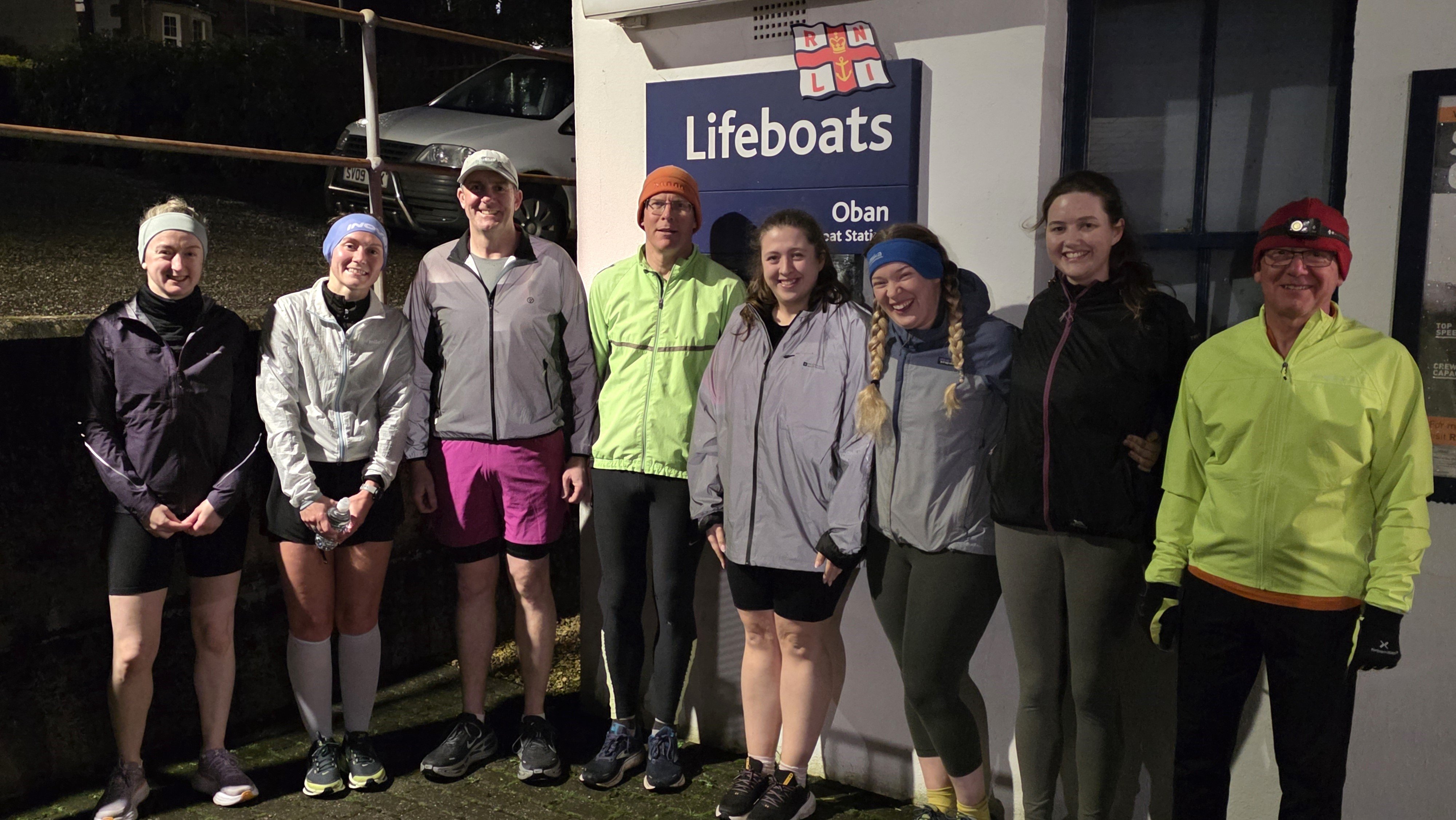 A group huddled in the lee of the lifeboat station in their running gear about to head off into the rain and wind.