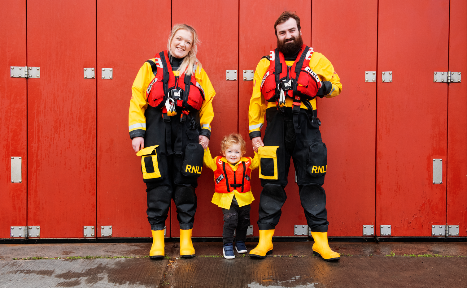 Landscape image of Emily, her husband Thomas and their son Harry, all in RNLI uniform