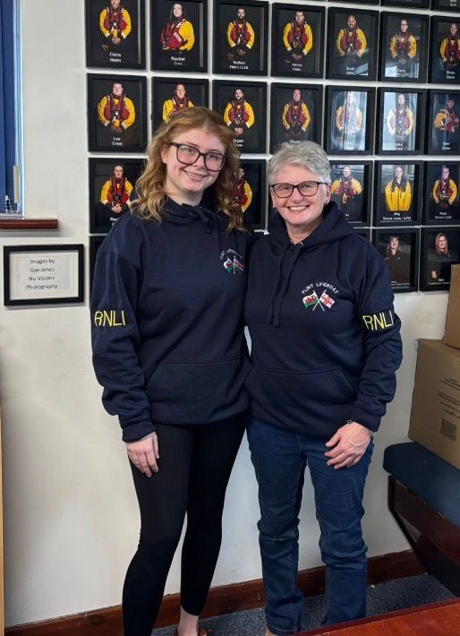 Portrait image of Lauren and Amanda in RNLI branded clothes, pictured at RNLI lifeboat station
