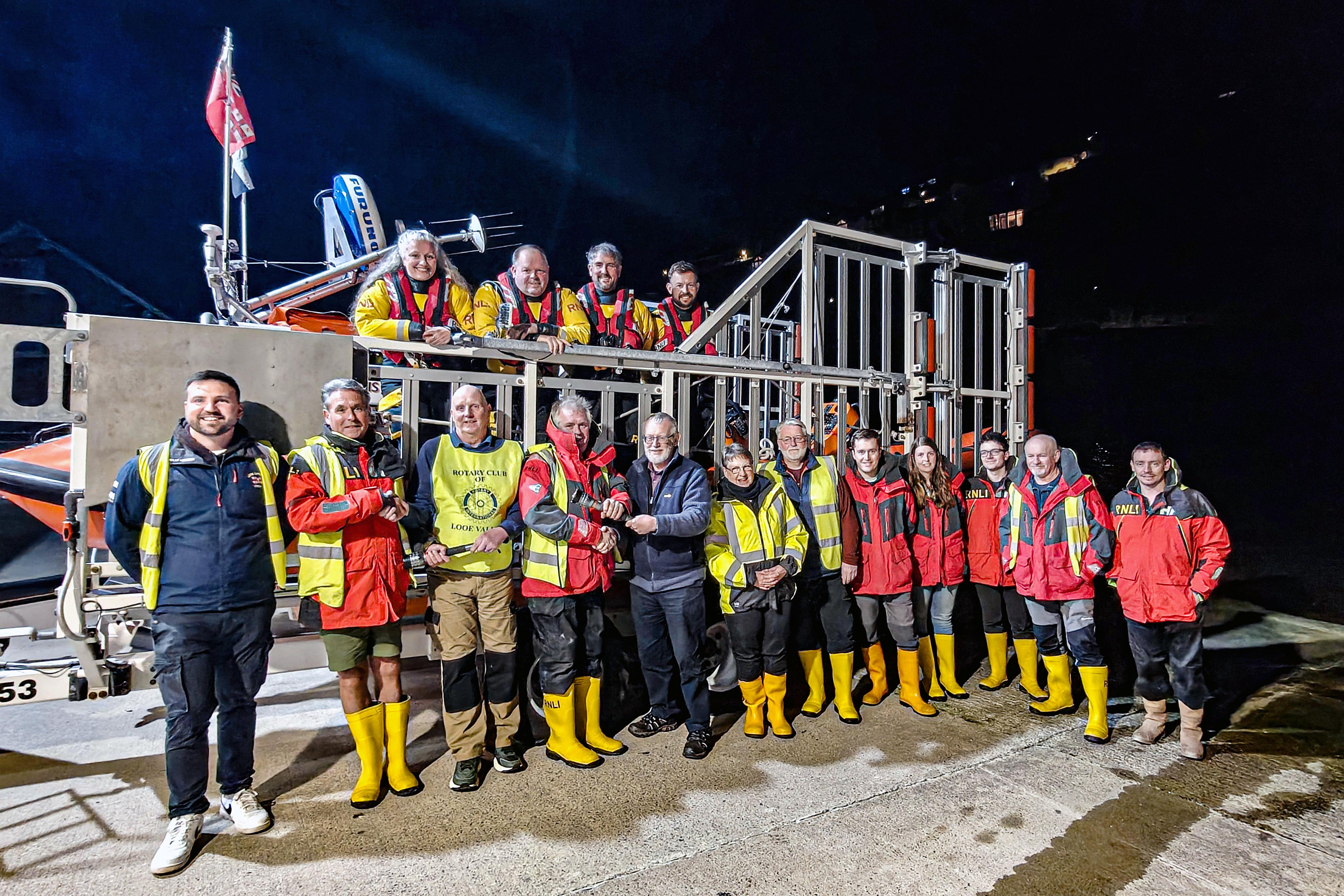 Looe Lifeboat duty Launch Authority Dave Robinson (right) and shore crew Paul Barley (left), accepting the torches from Paul Roach (right) and David Bunt (left) with members of Looe RNLI volunteer crew