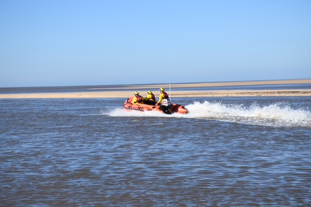 Wells RNLI D class lifeboat on open water with a crew of three in full RNLI branded kit
