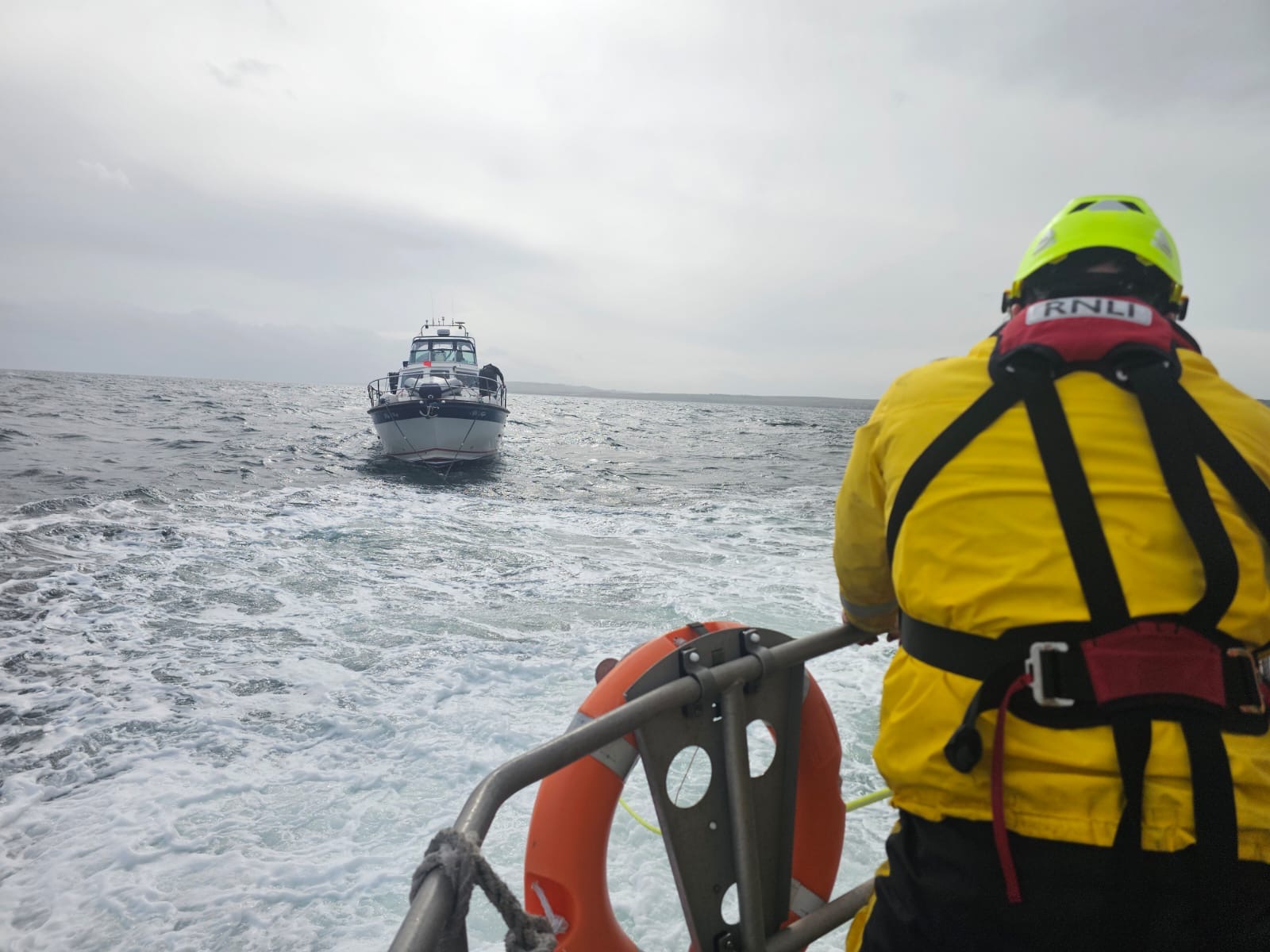 Eyemouth RNLI crew tow a motor cruiser that had suffered engine failure NE of St Abbs Head. Picture shows a crew member at the rear of Eyemouth lifeboat with the towed boat in the background.