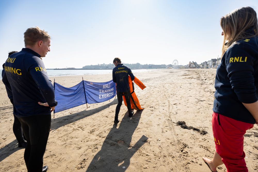 RNLI lifeguards on Weymouth beach carrying out casualty care 