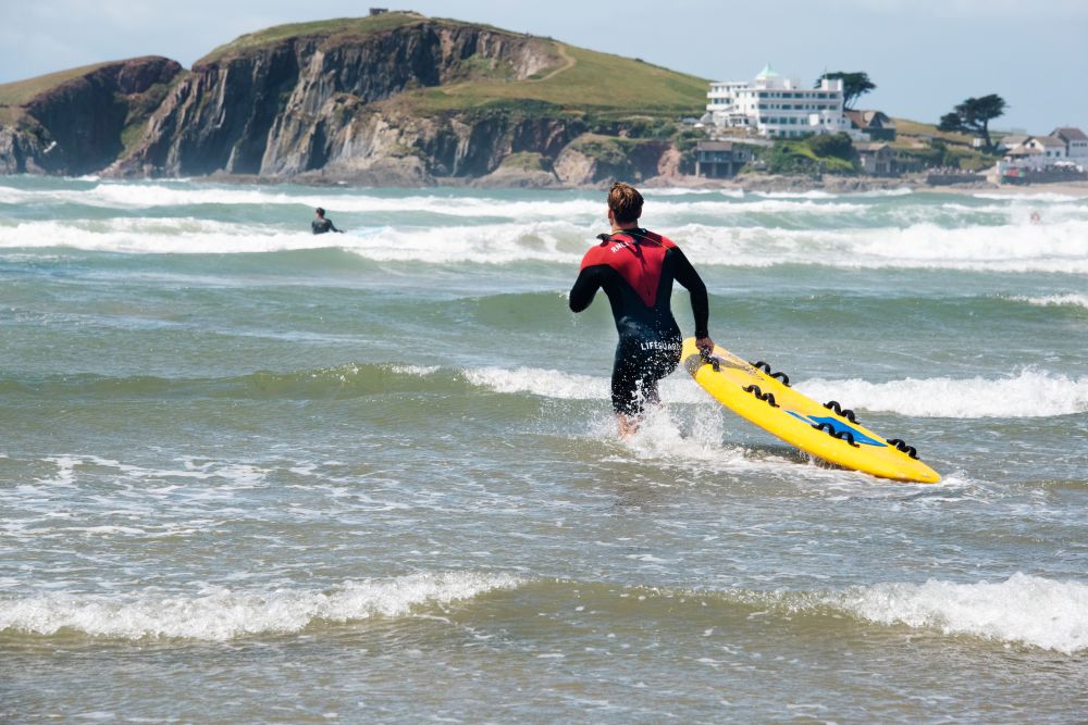 RNLI lifeguard entering the water with a rescue board