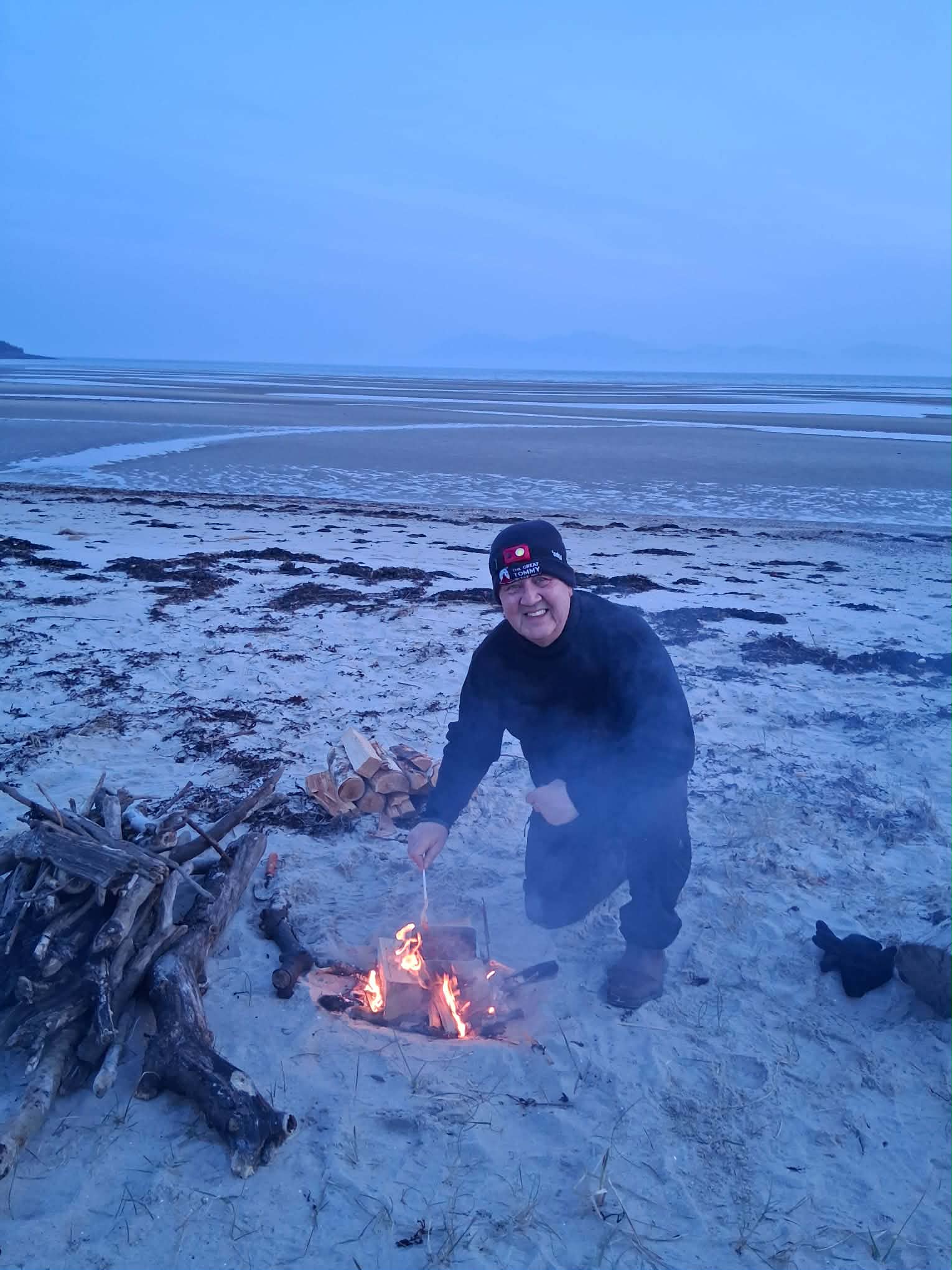 Volunteer David Mackail builds a campfire in the sand at Kilbride Bay in preparation