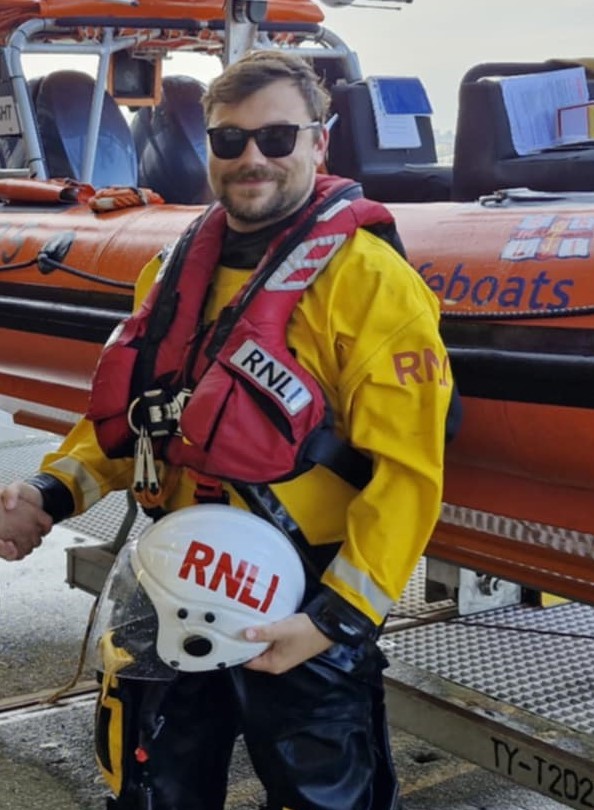 Tyler Bonham A85 helm standing in front of A85 lifeboat Julia and Angus Wright