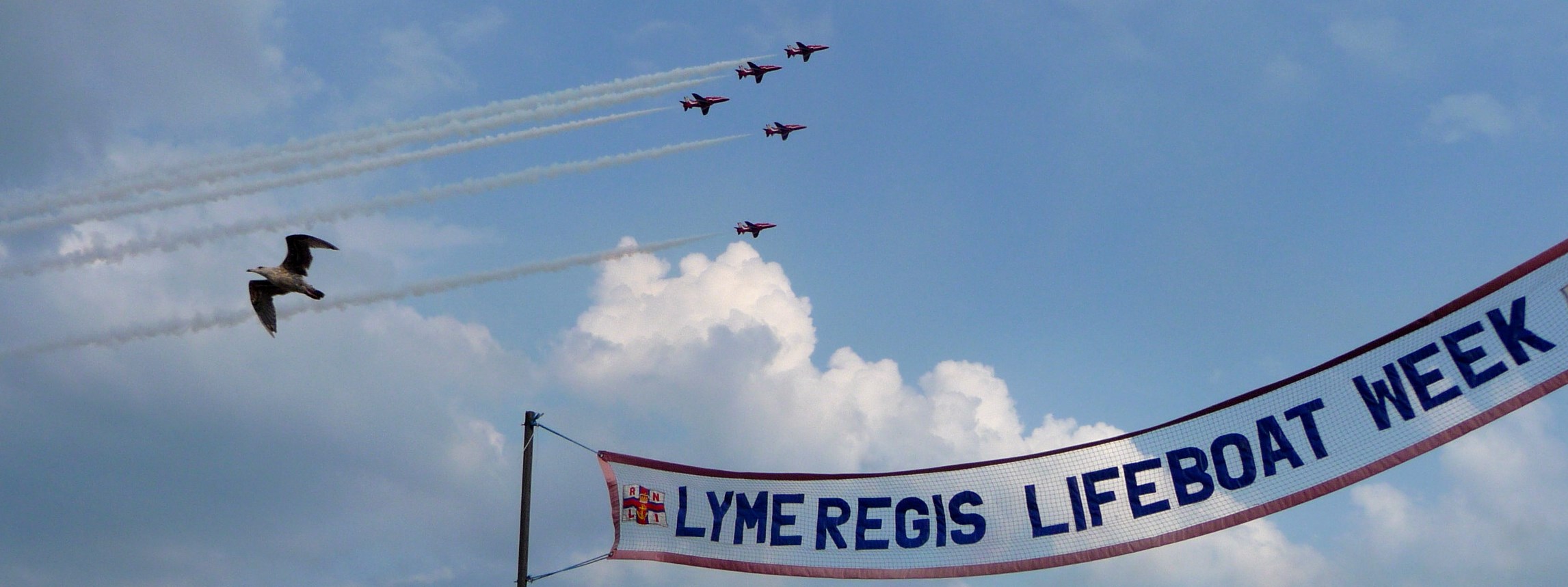 red aeroplanes above Lifeboat Week banner against blue sky
