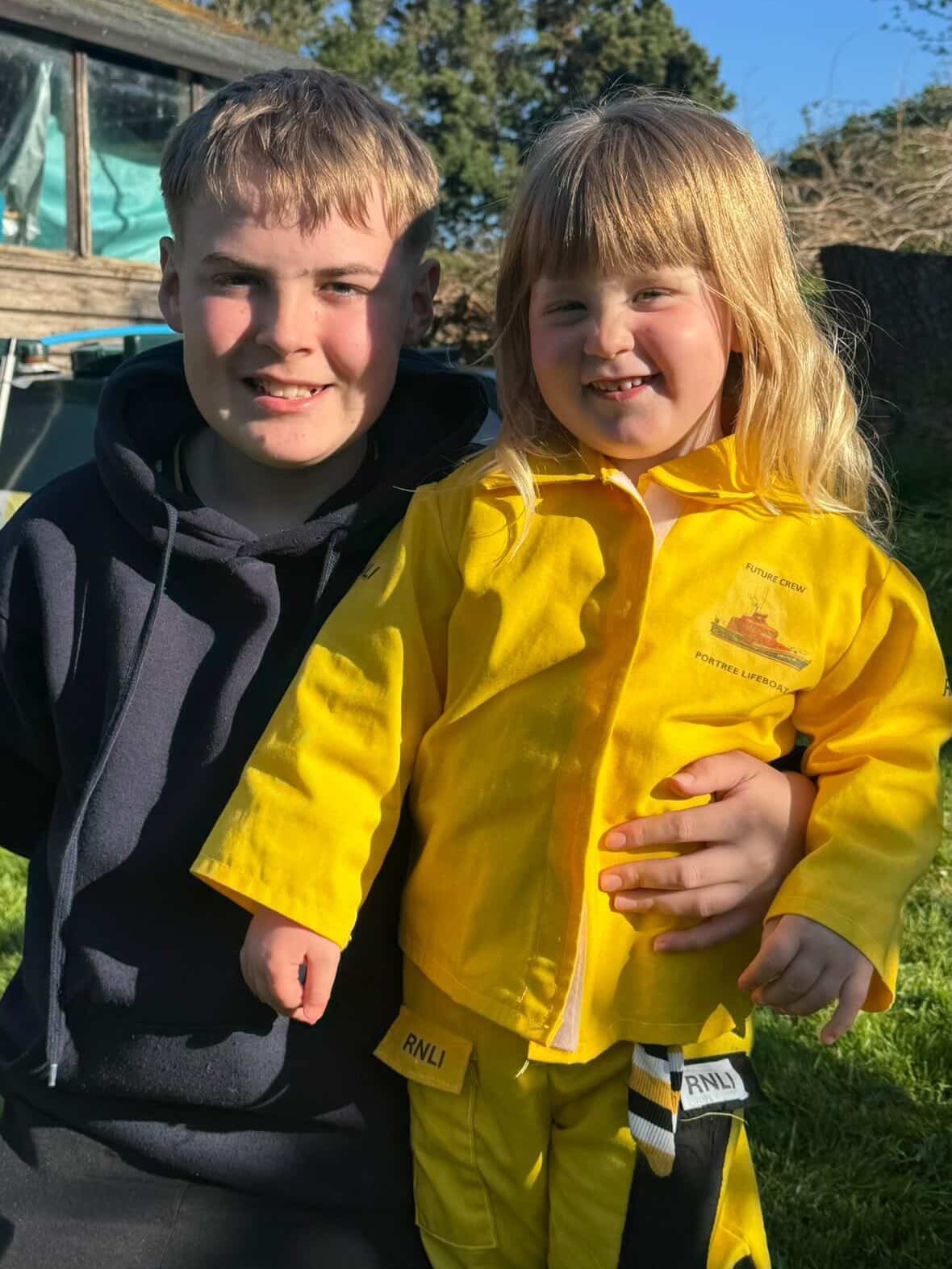 Brother and sister Angus and Georgie, dressed in yellow overalls and Portree RNLI hoodies, are ready to start their RNLI Mayday Mile fundraising challenge!
