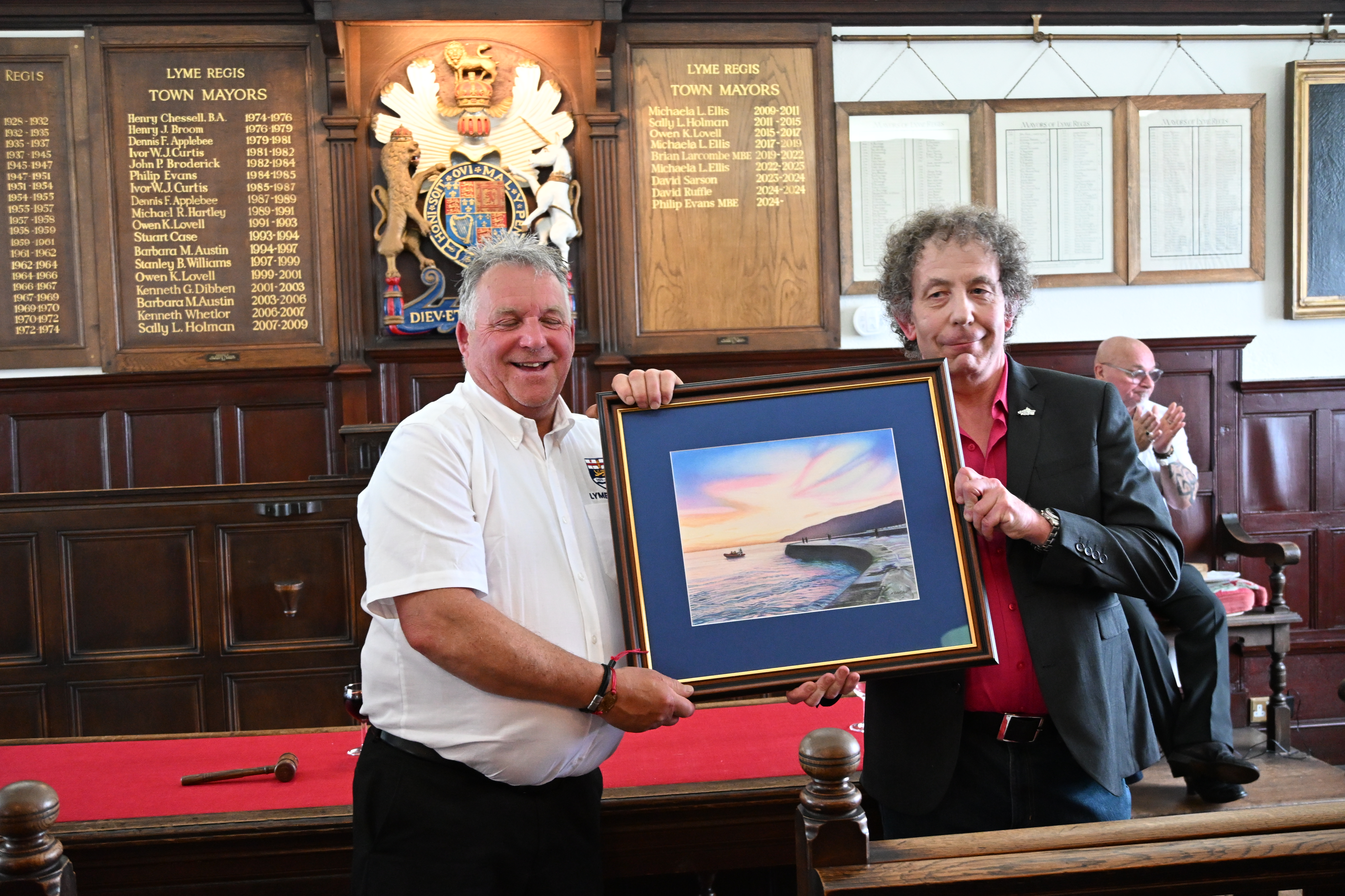 Man in white receiving artwork from man in black