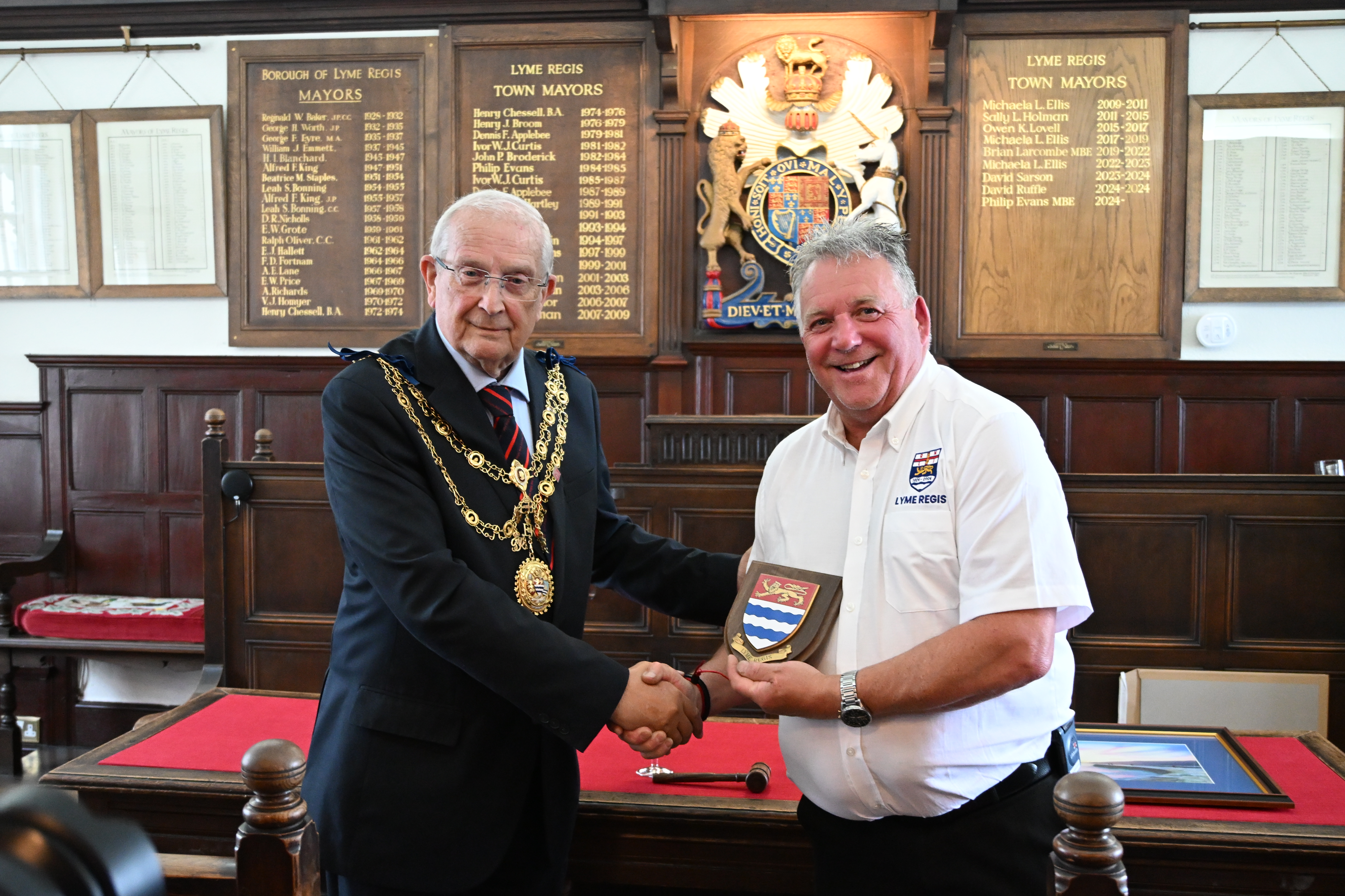 Man in mayor chain presenting shield to man in white top