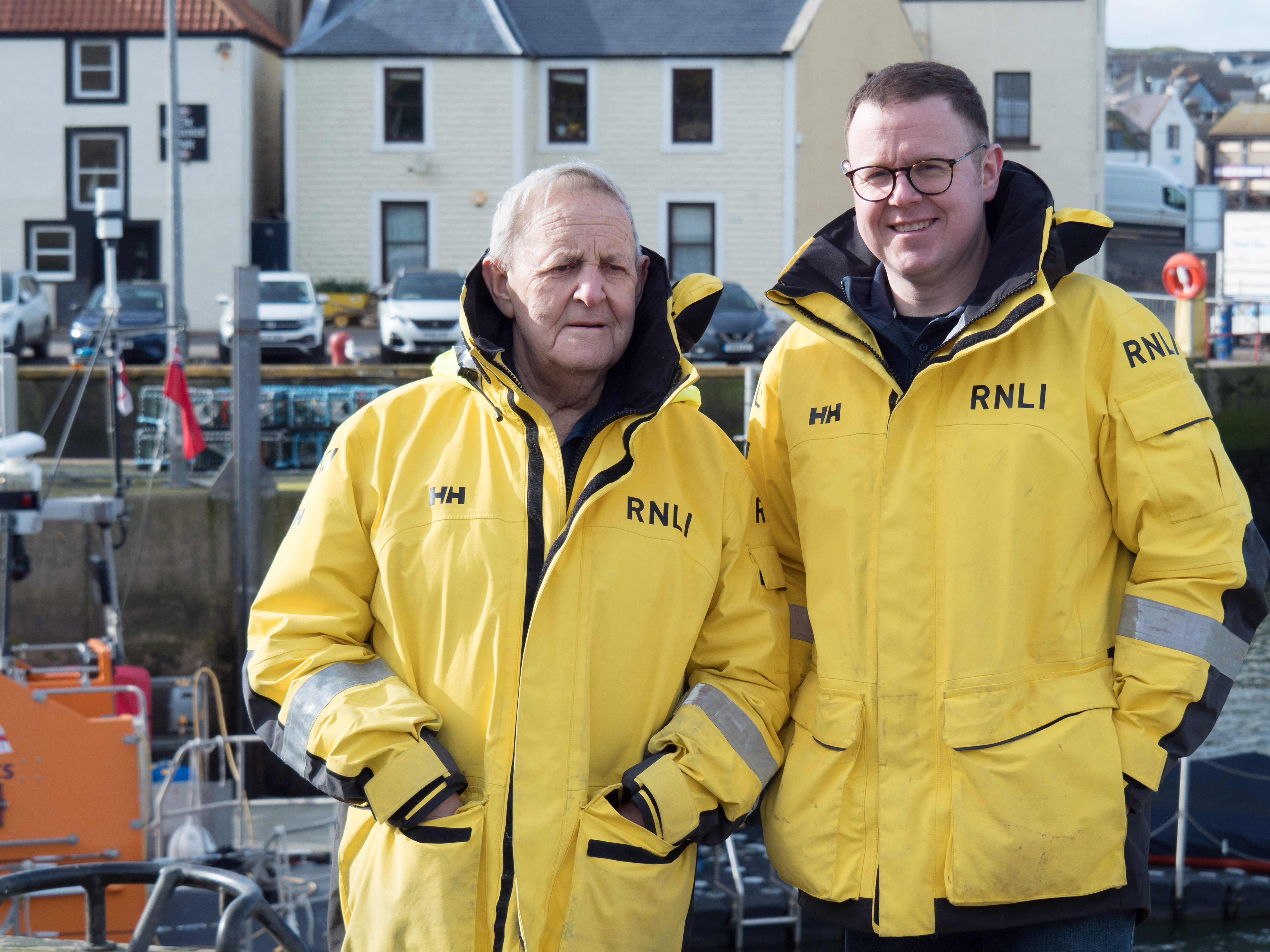 Dean Mark pictured with his late grandfather Alistair 'Spike' Crombie who was on the Eyemouth crew for many years. They are pictured standing together wearing crew yellow jackets, at Eyemouth harbour