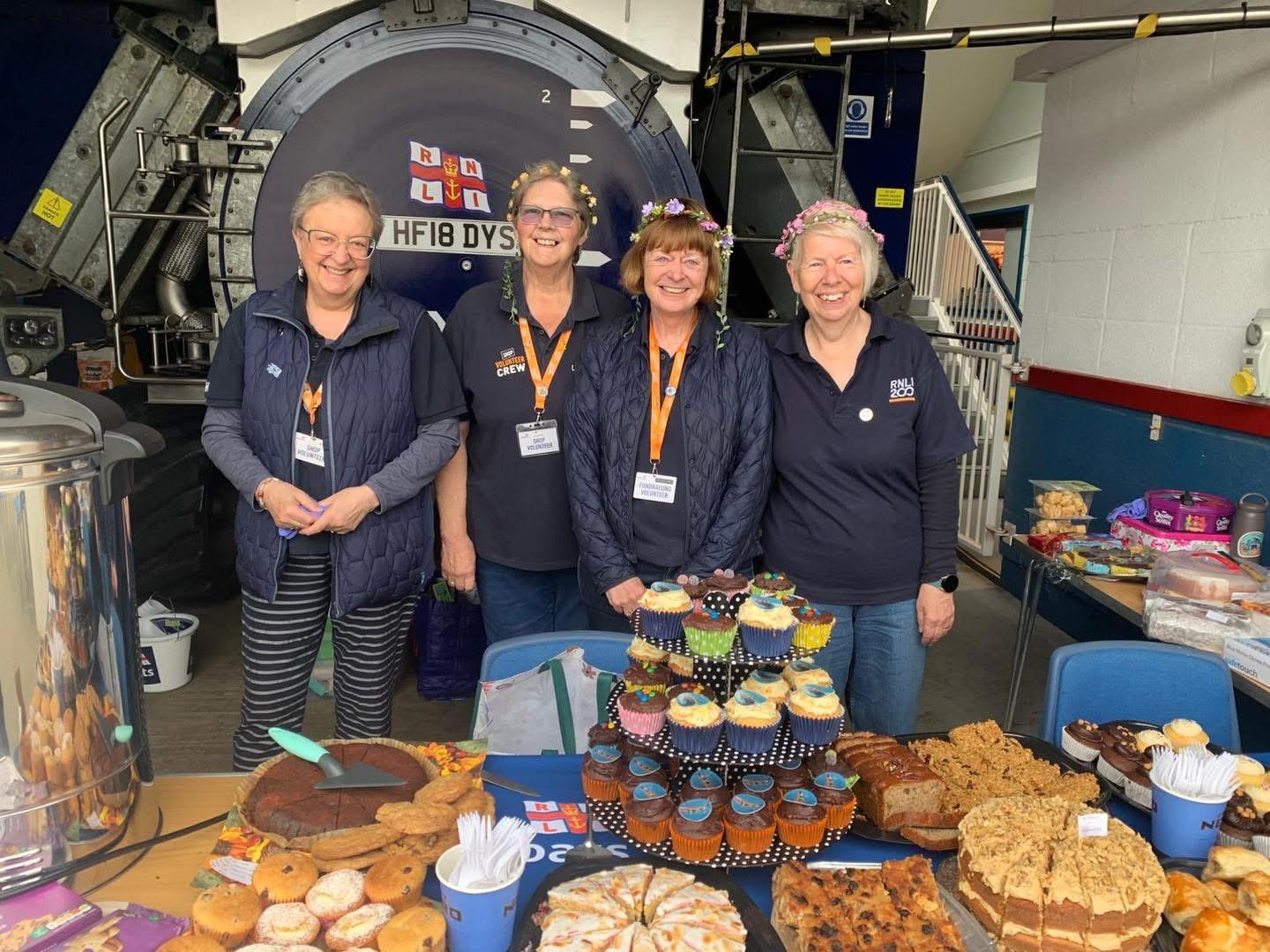 volunteer team standing behind table stacked with cakes