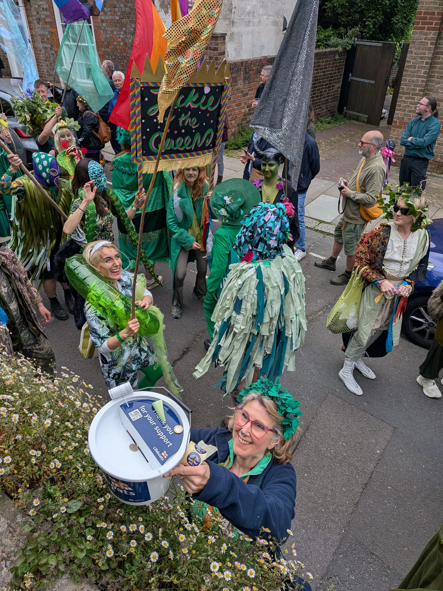 A volunteer in a parade lifting a bucket for a donation