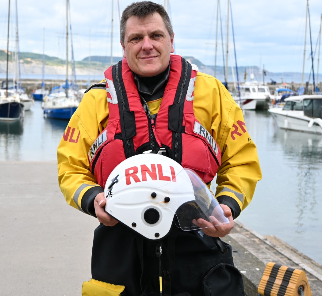 man in lifeboat drysuit in front of harbour
