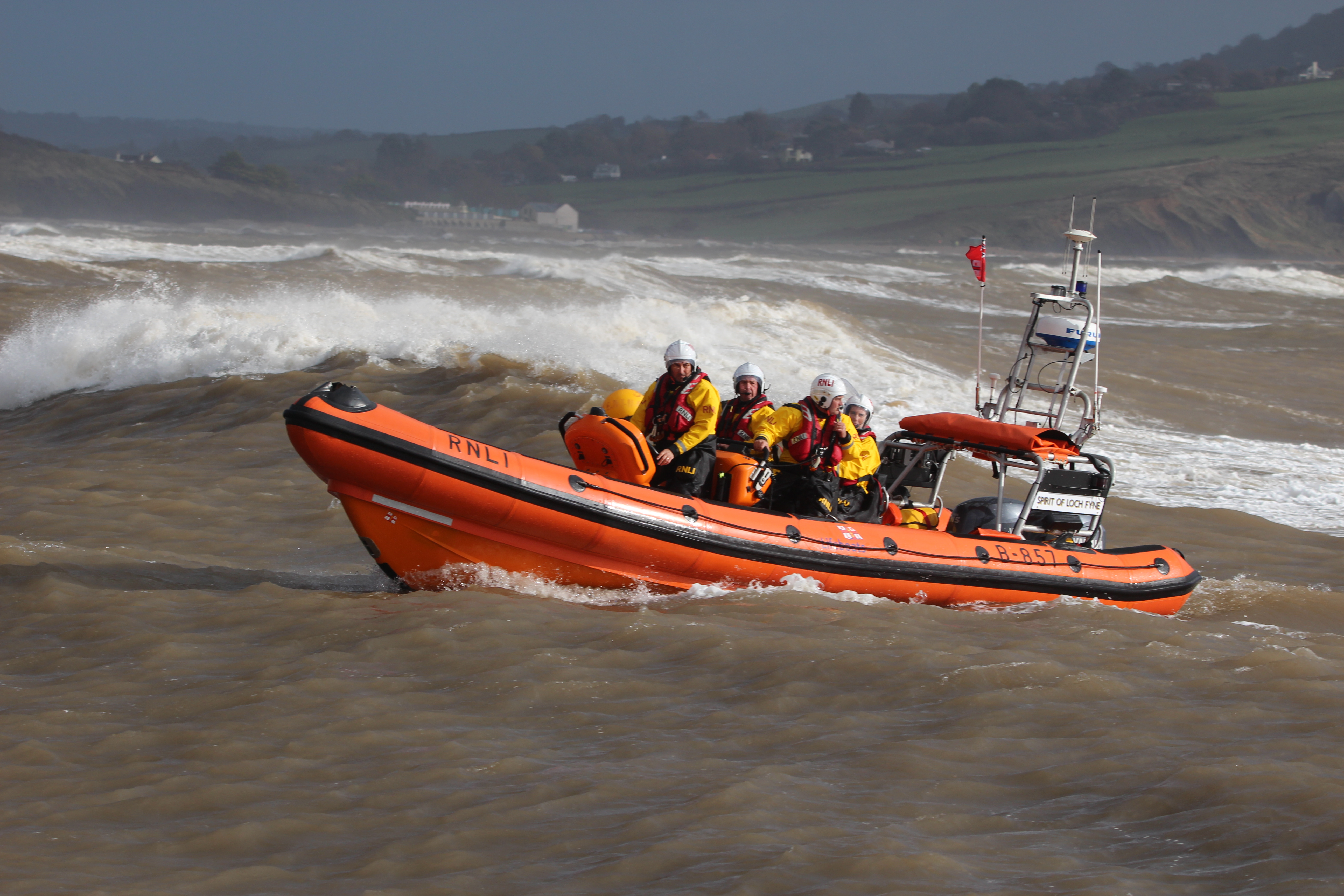 Orange lifeboat at sea with large waves