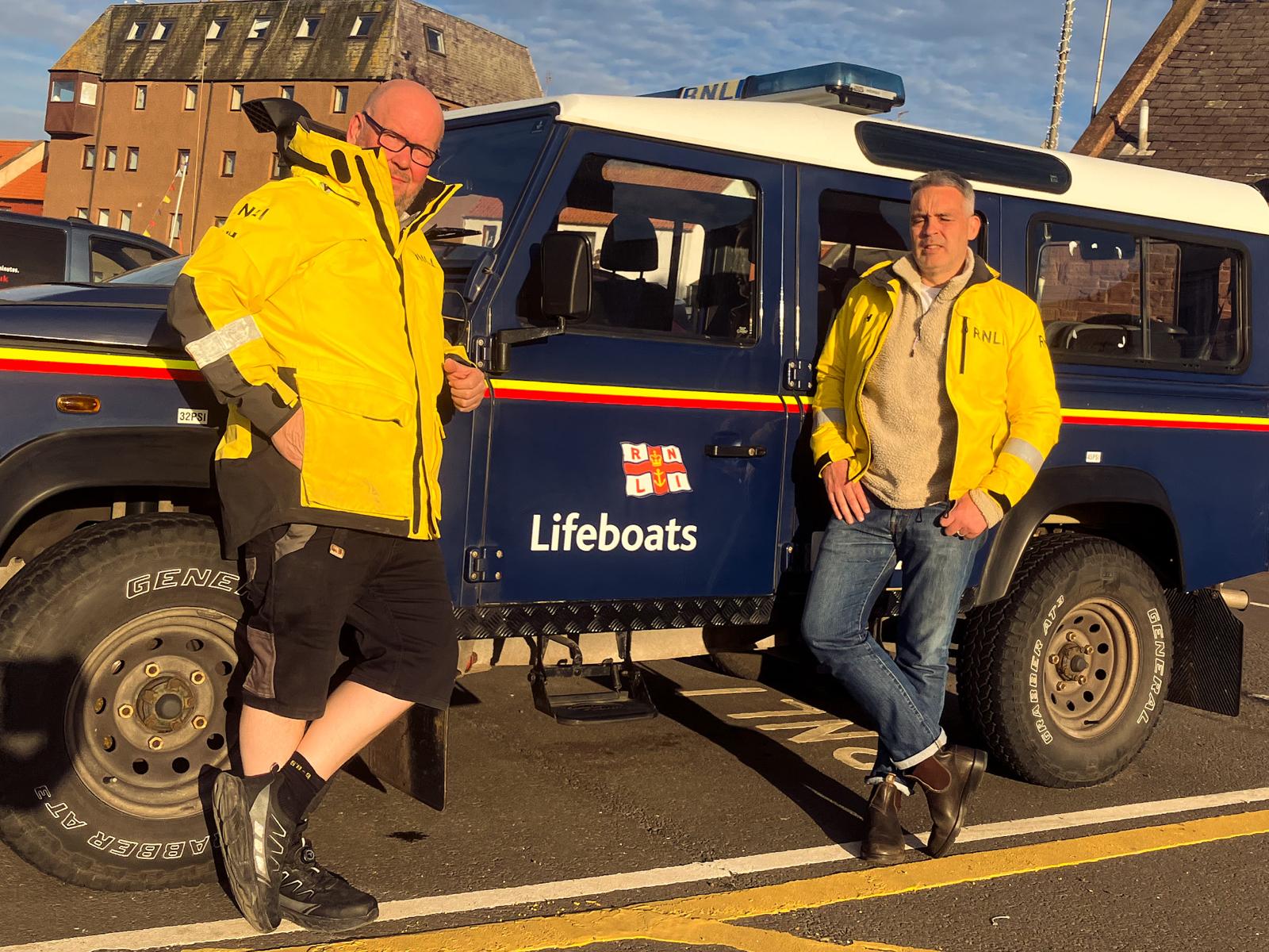 Two men in front of vehicle.