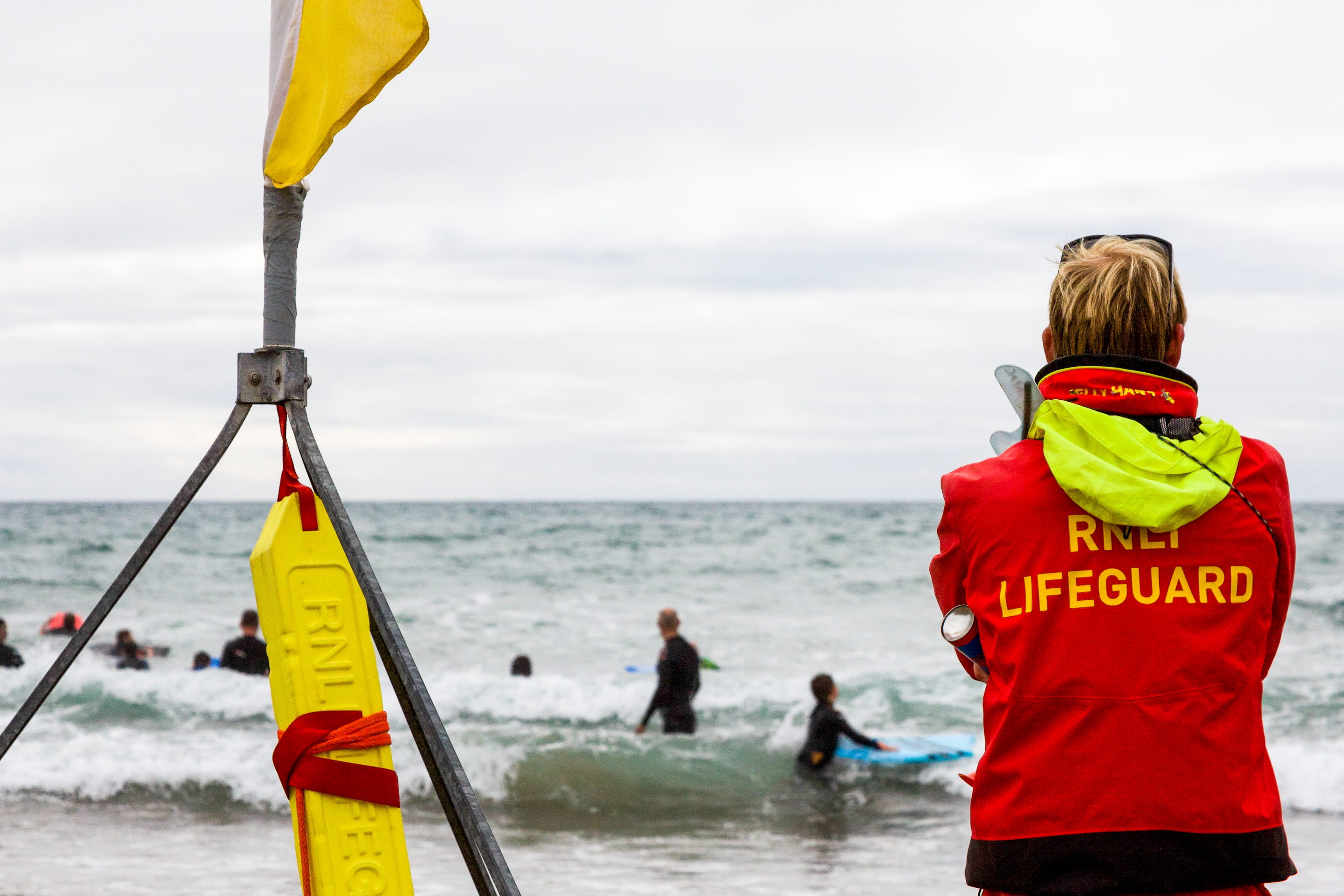 An RNLI lifeguard keeps watch on beachgoers as they enjoy the nearby surf.