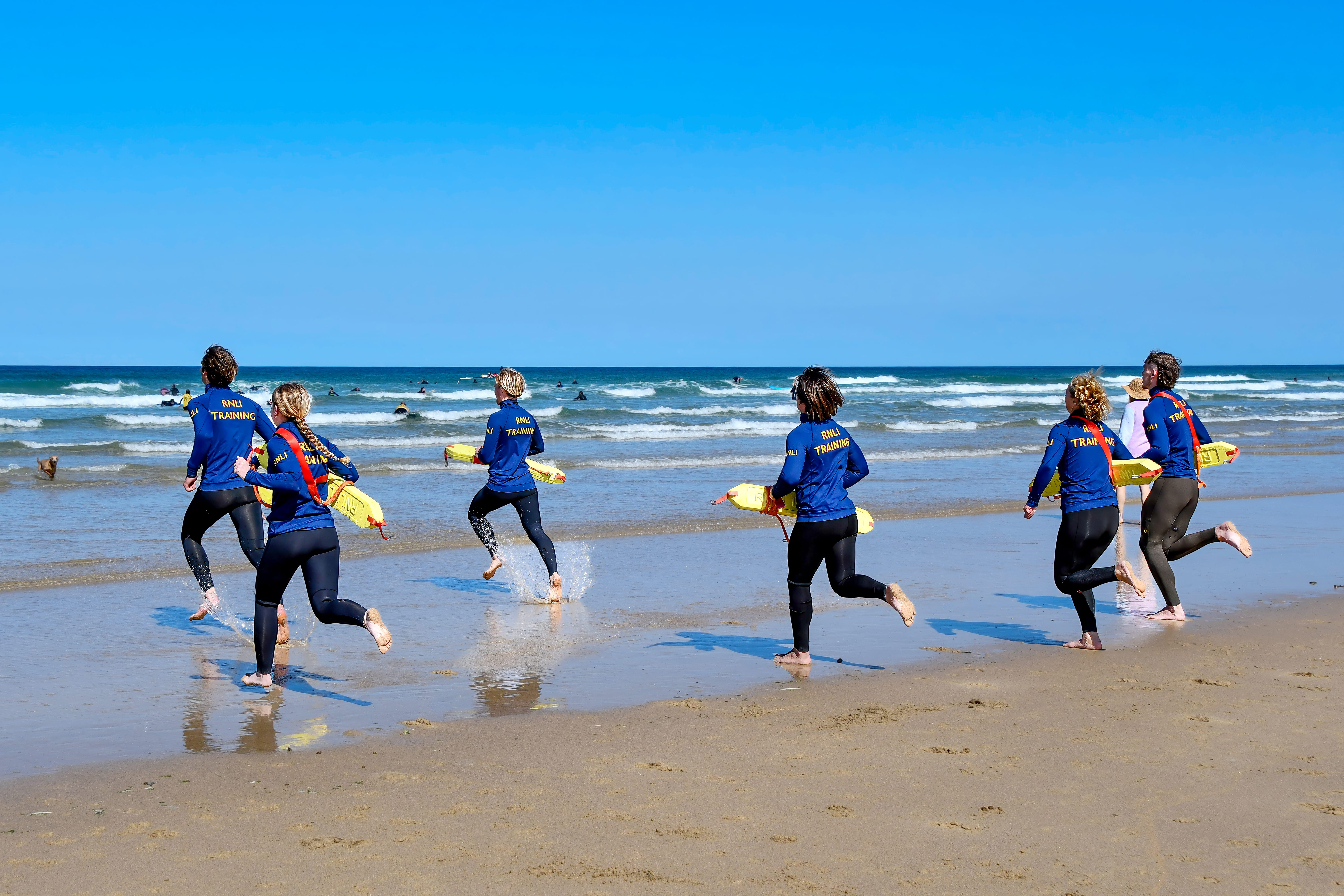 A group of lifeguards run towards the sea during their training with the RNLI.