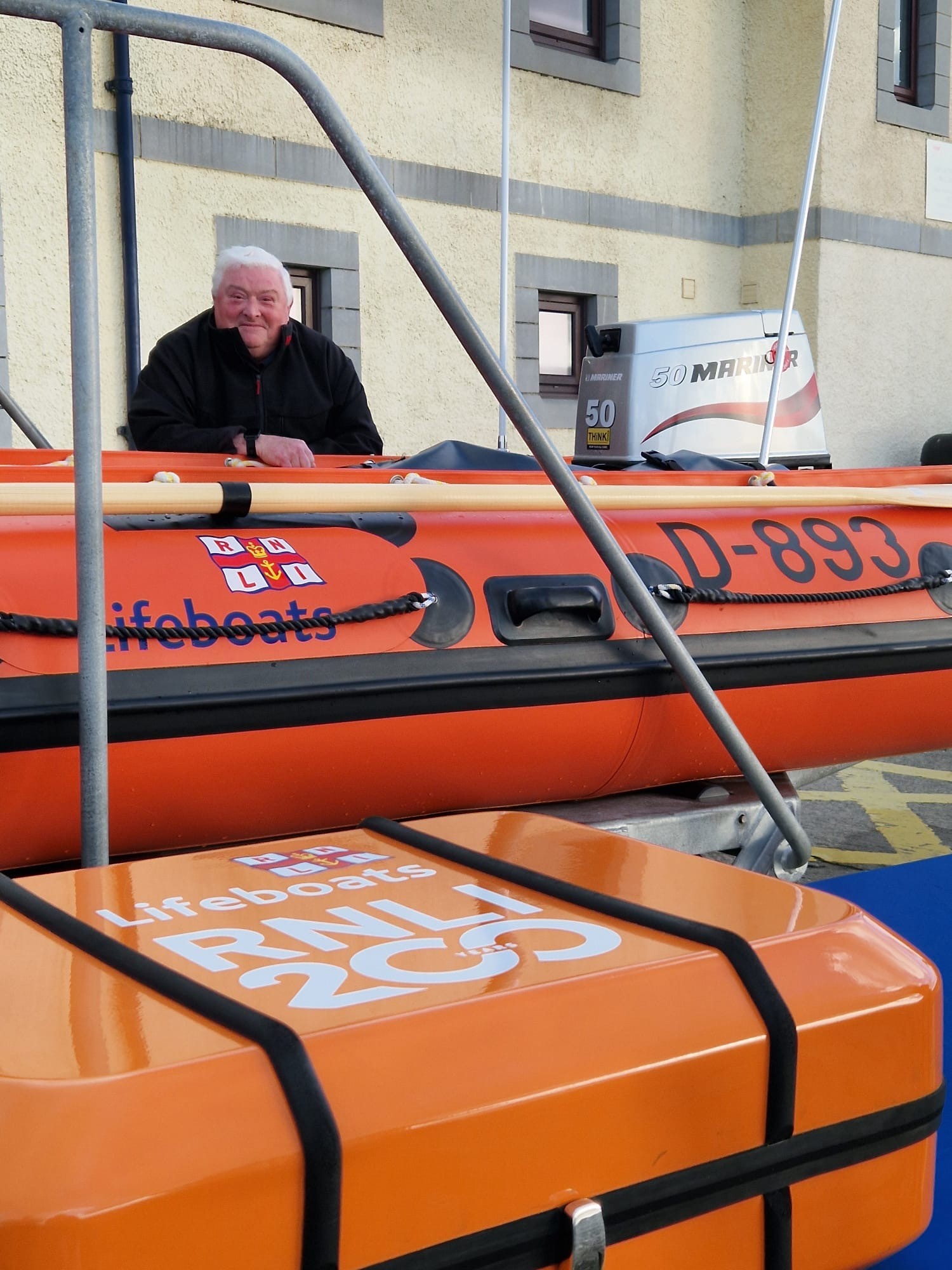 Portrait image of Ron stood leaning on a D class RNLI lifeboat