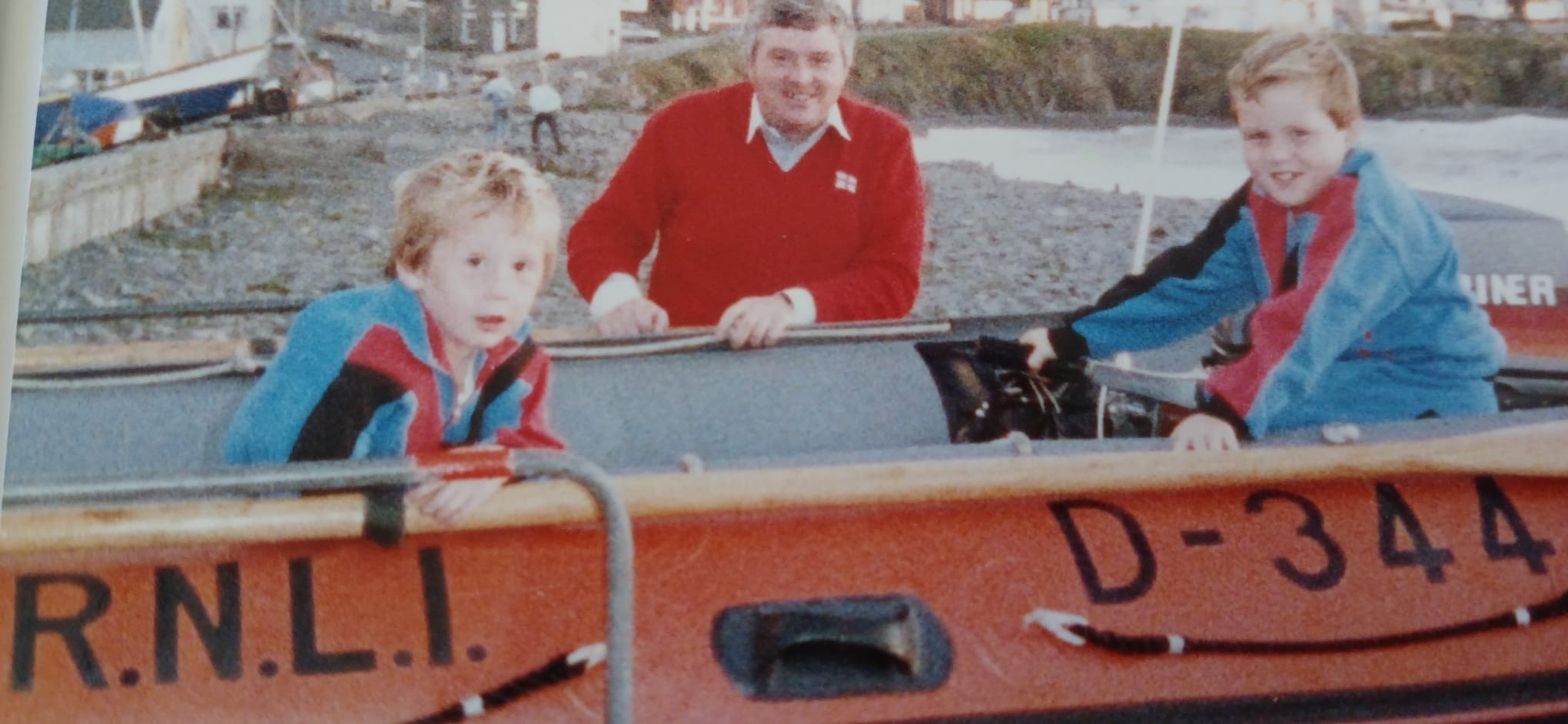 Landscape image of Ron and his two sons sat in the D class RNLI lifeboat