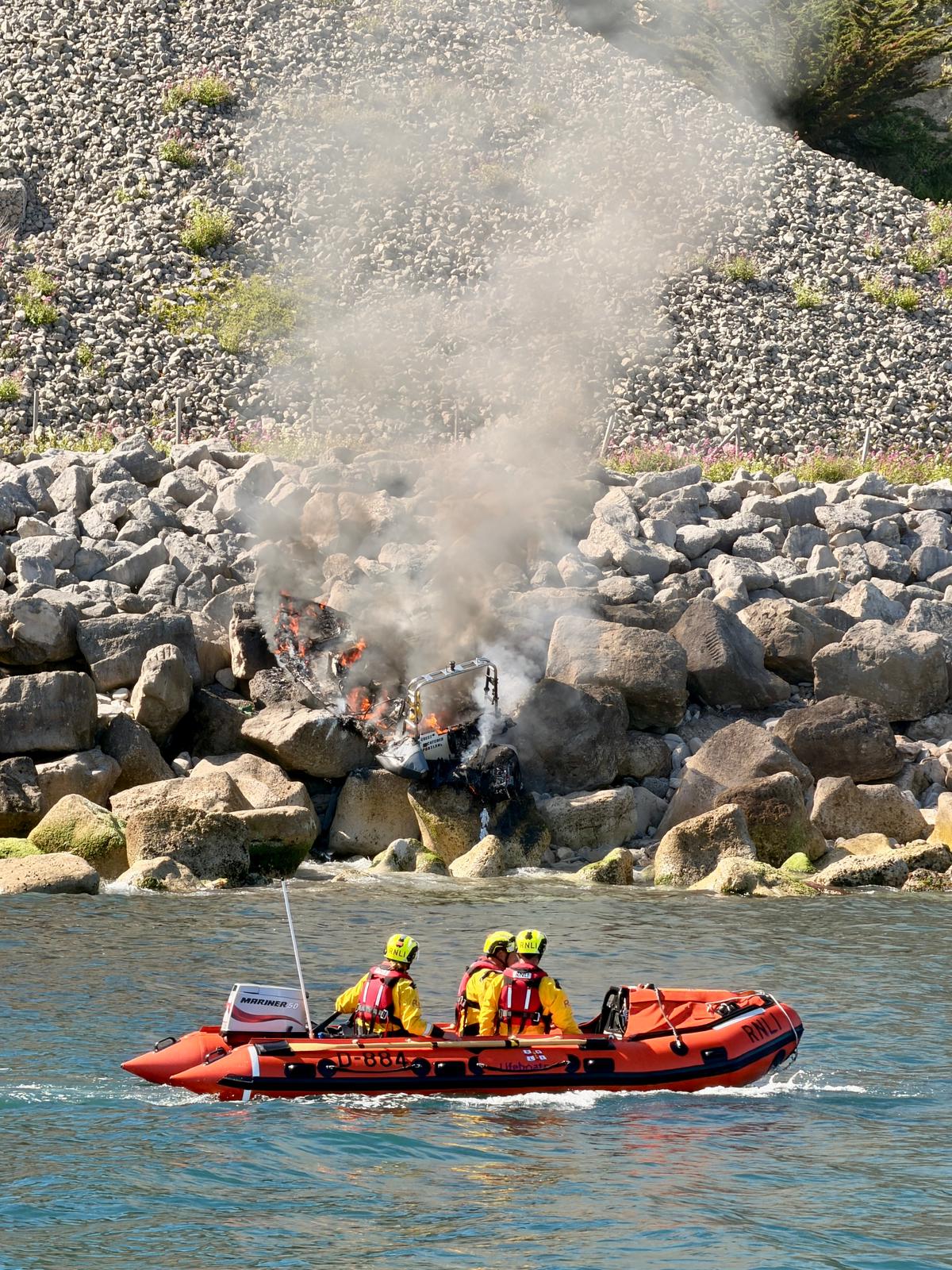Swanage inshore lifeboat assessing the burning boat from a safe distance